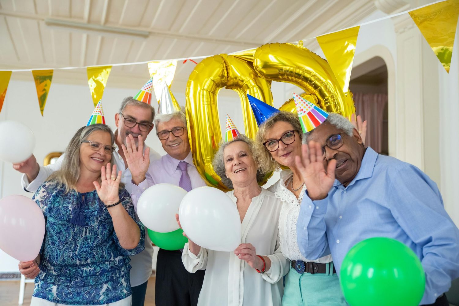 Group of seniors celebrating at a party with yellow bunting decorations and colorful balloons.
