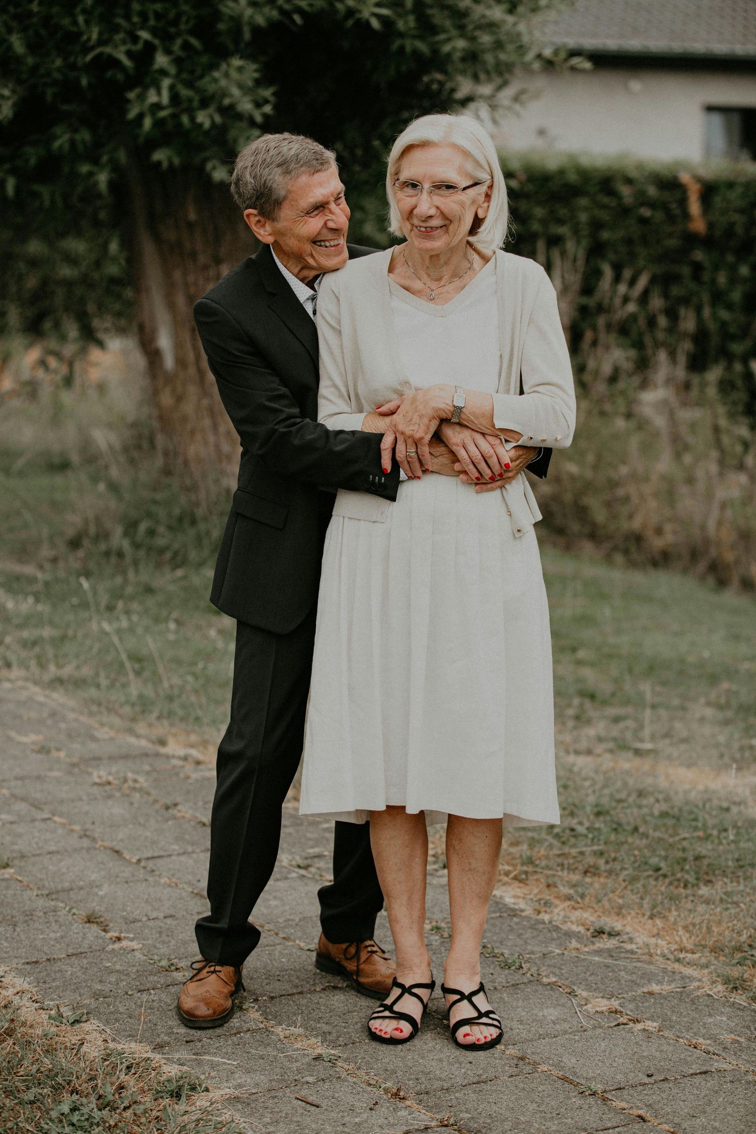 An elderly couple embraces and dances together outdoors in a romantic moment captured in a series of intimate photos.