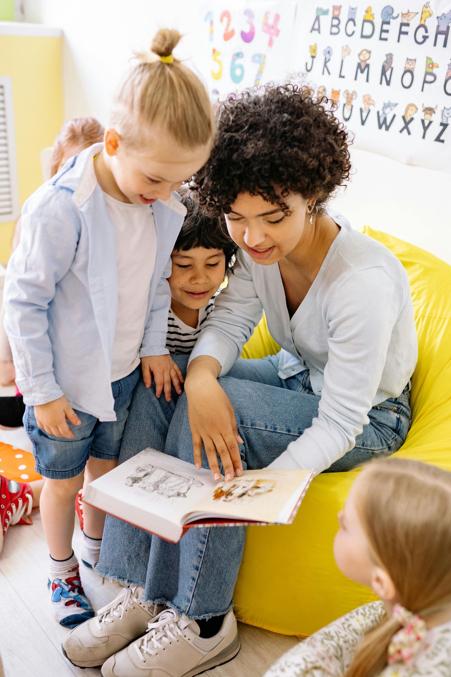 Queen Creek  Arizona Daycare Photography Students gathered around books and learning materials in a modern classroom environment.