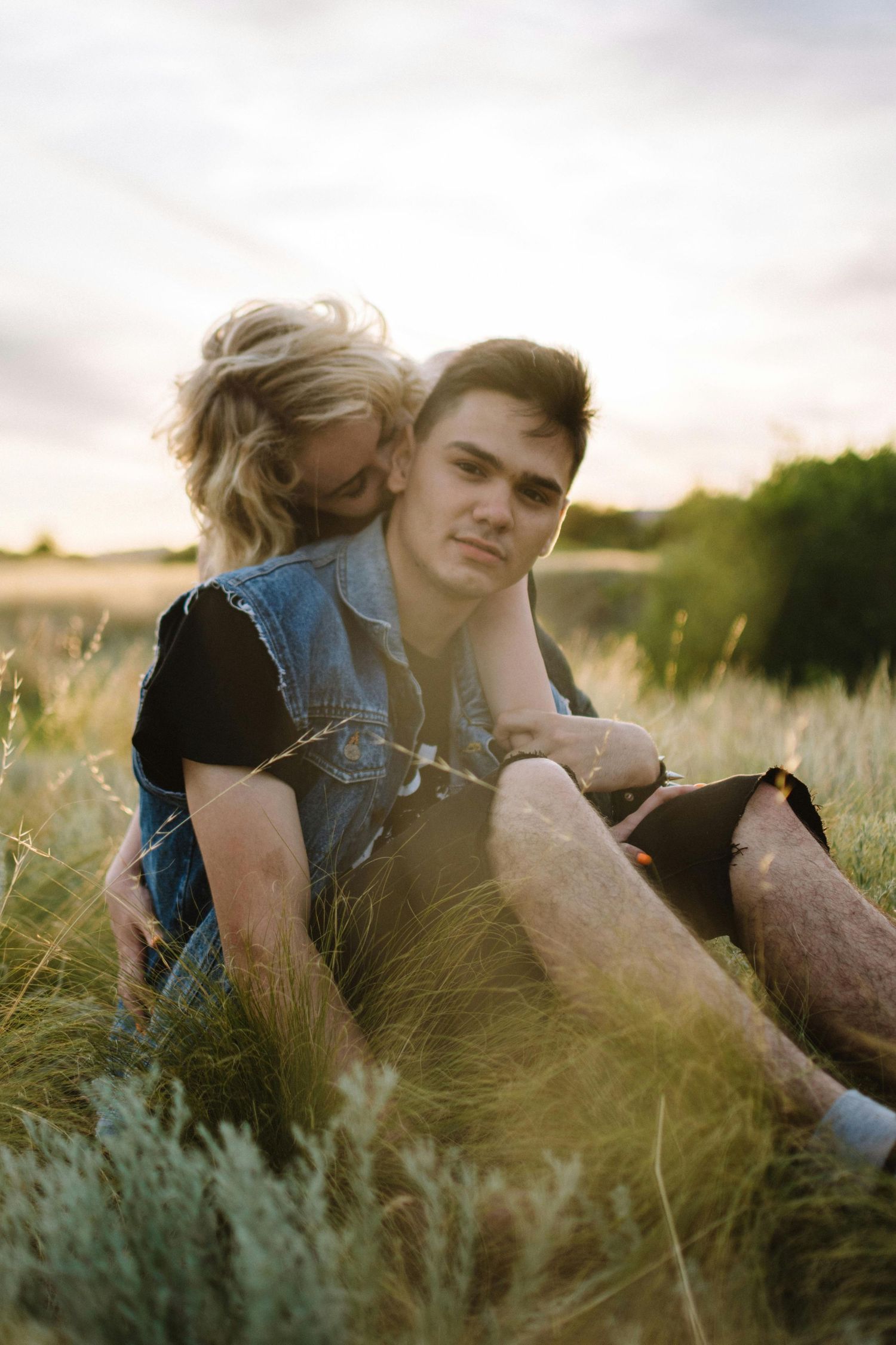 Couple relaxing together in a golden sunlit meadow with tall grass during sunset. Top Photographer Scottsdale.