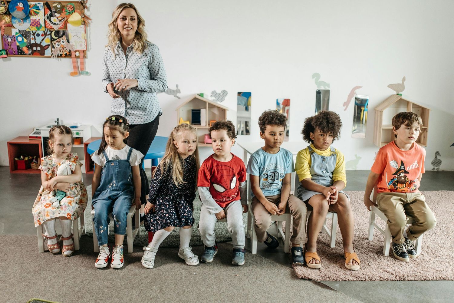 Arizona Daycare Photography Group of students sitting together against white wall during class activity.