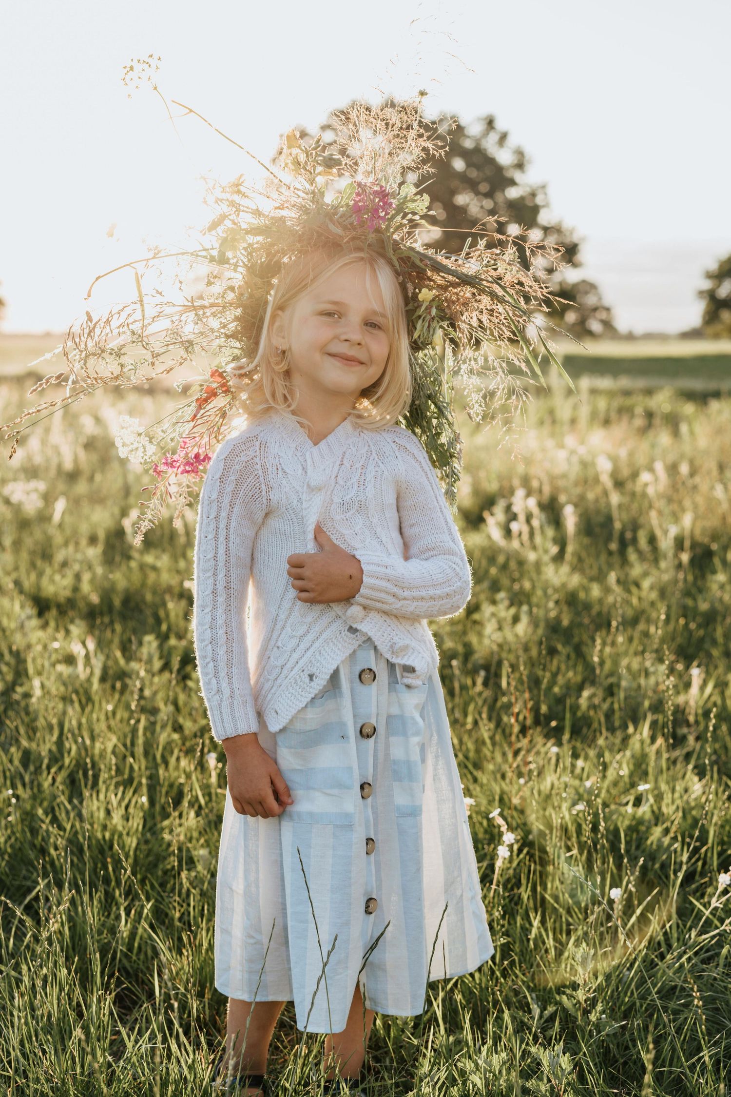 Children's outdoor photography Flagstaff Arizona people in white outfits embrace while standing in a sun-drenched field of tall grass.