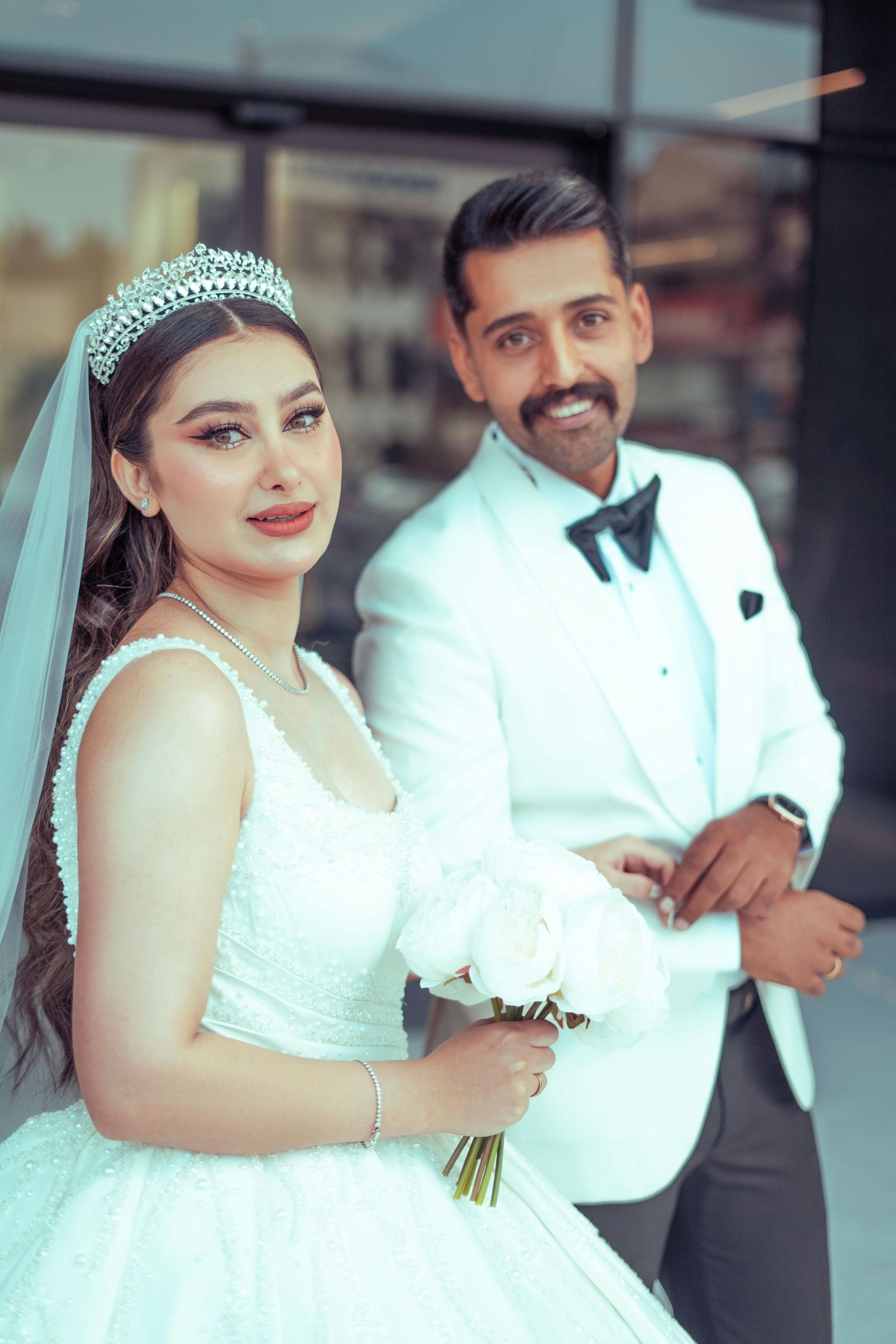 A wedding couple poses together, with the bride wearing a white dress and tiara while holding a bouquet. Award Winning Photographer  AZ