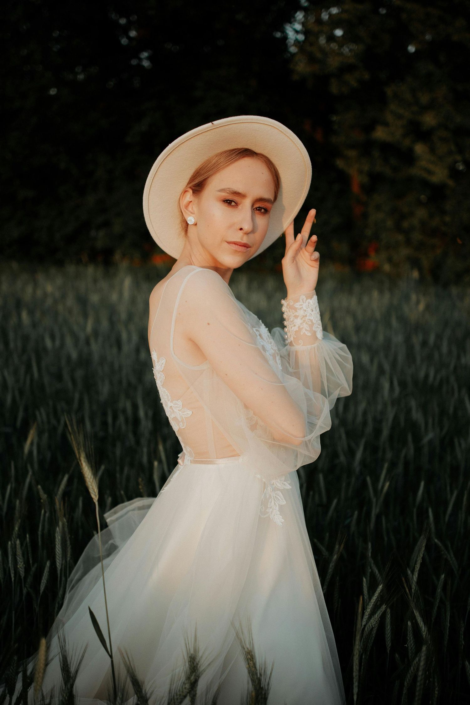 Ethereal bridal portrait in a white gown and sun hat against a moody field of agave plants.  Trusted Sedona Photographer.