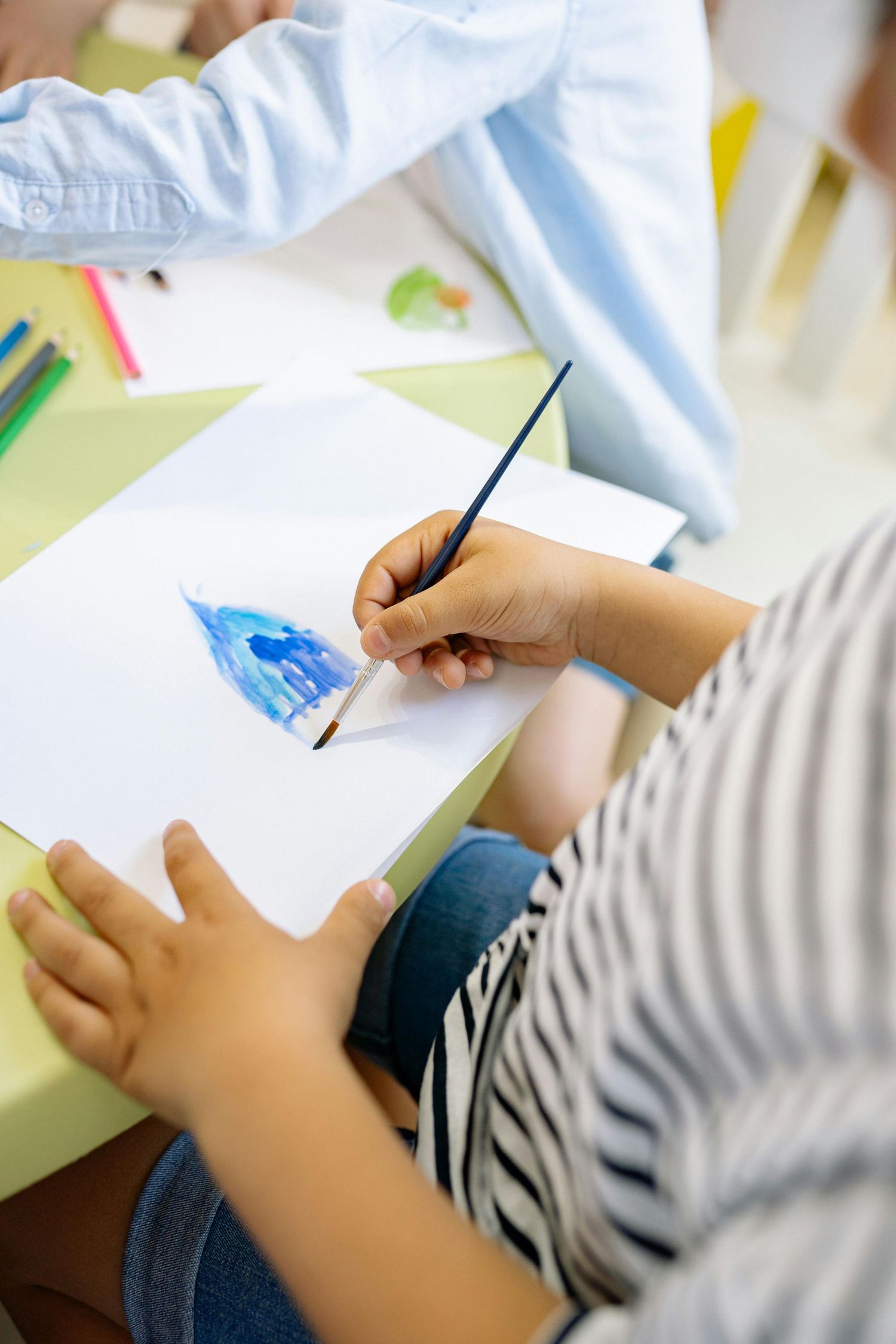 Close-up view of hands writing and drawing on paper during a classroom activity. Peoria Vistancia.