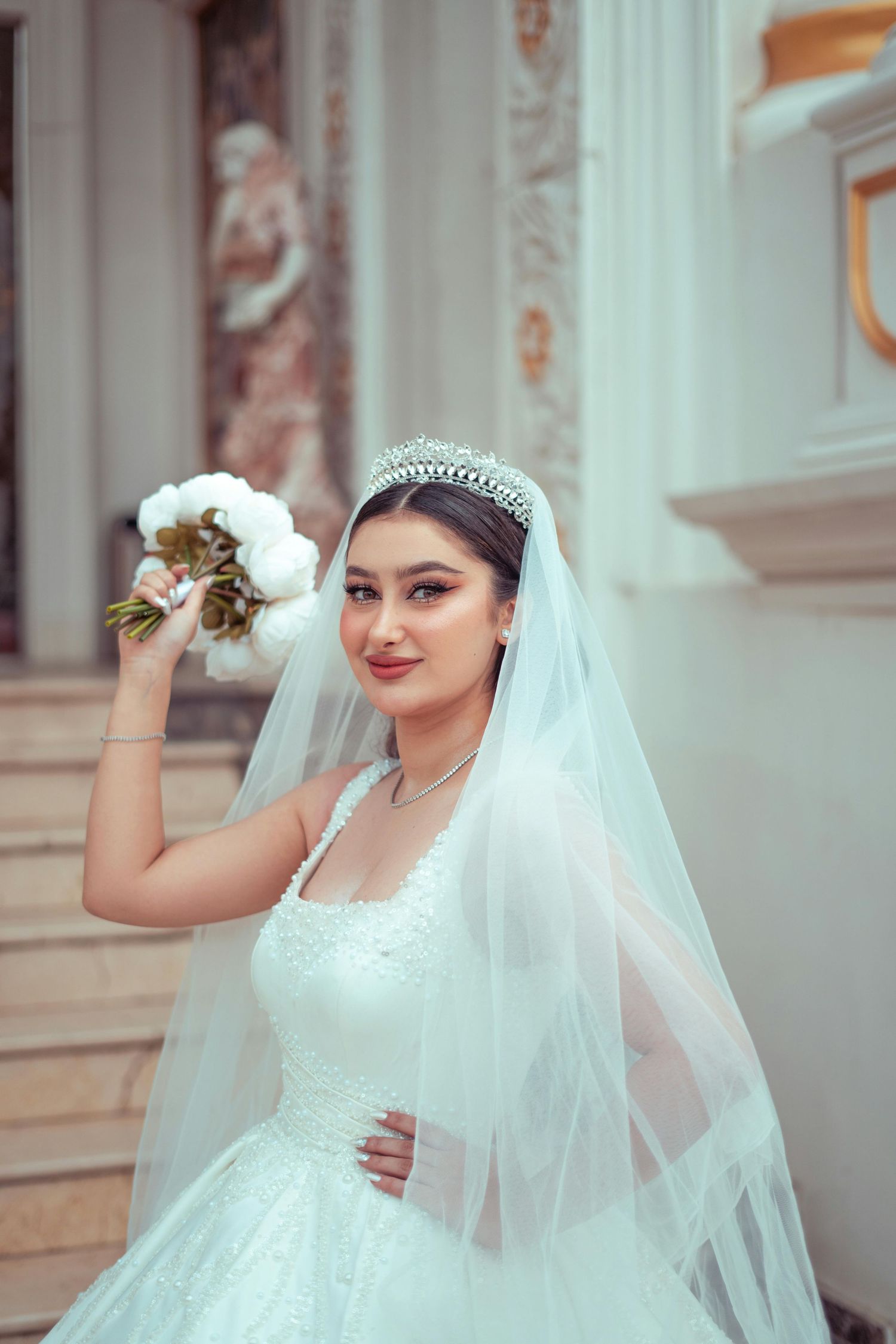 Beautiful bride in white lace wedding dress with flowing veil and tiara poses elegantly with bouquet. Award Winning Photographer Tempe