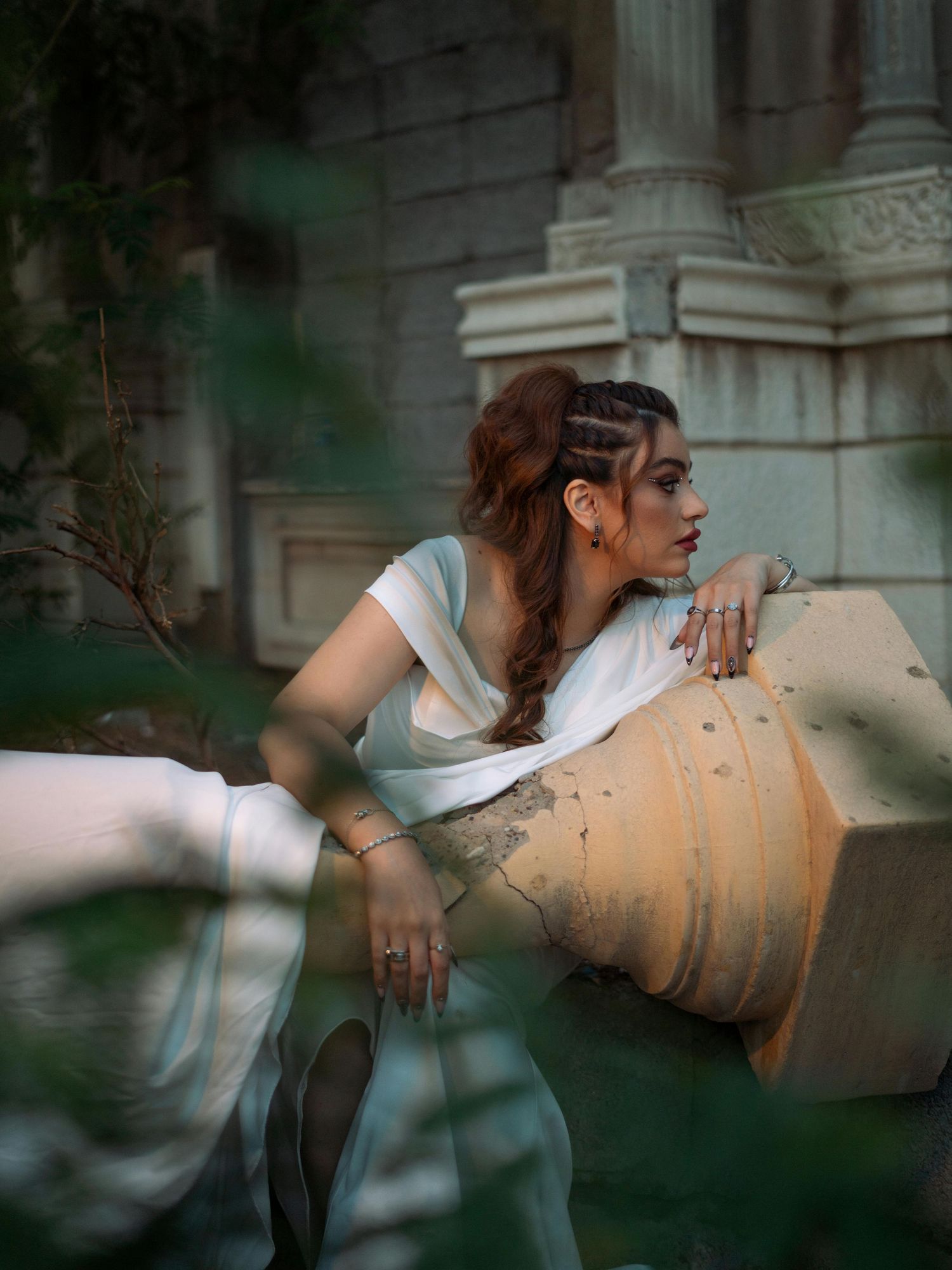 A person in a white top leans against a beige amphora vase in a dreamy outdoor garden setting. Trusted Flagstaff Photographer.