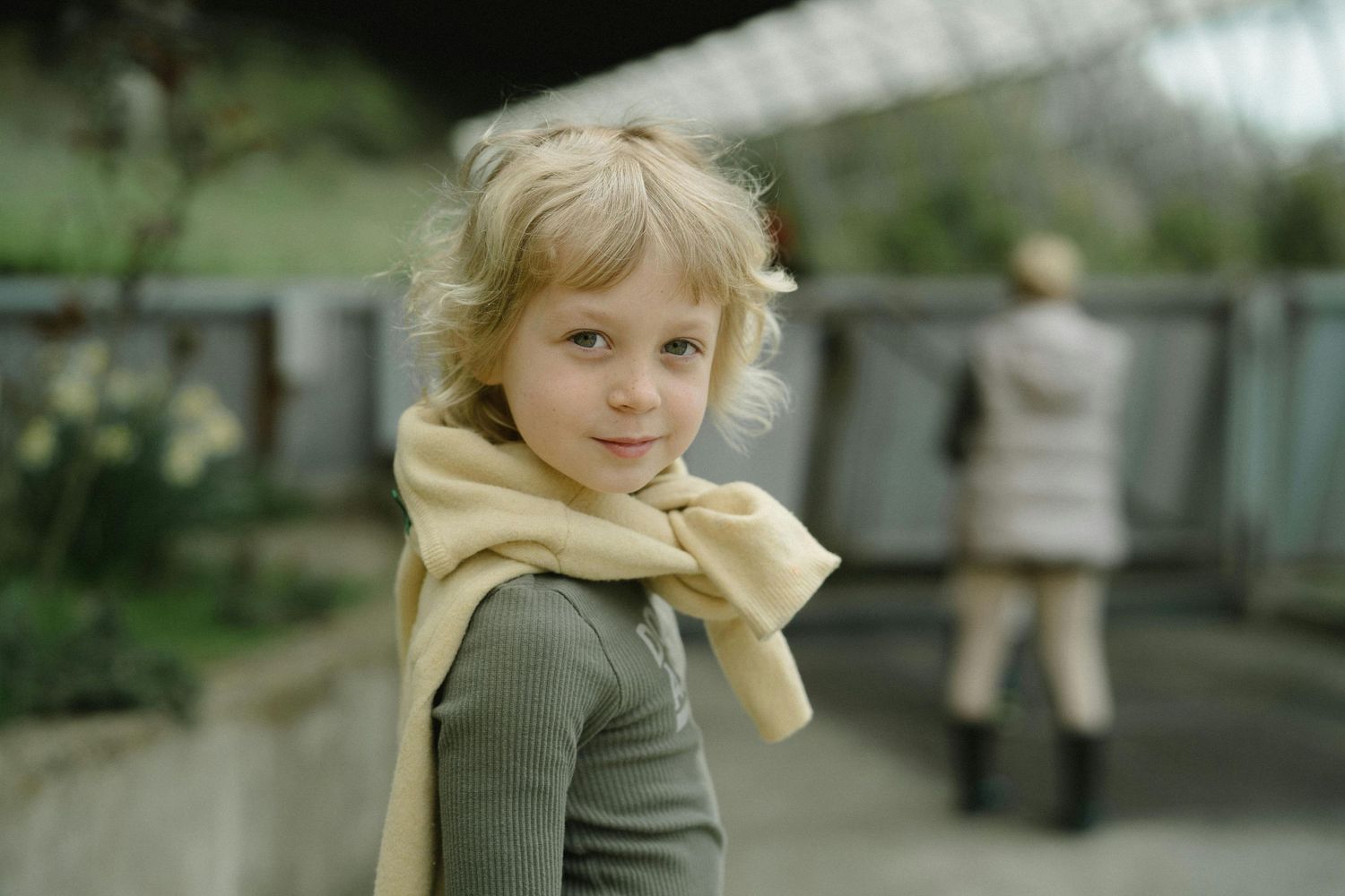 San Tan Valley Arizona Family Photography A child in olive clothing and yellow scarf poses outdoors on a cloudy day.