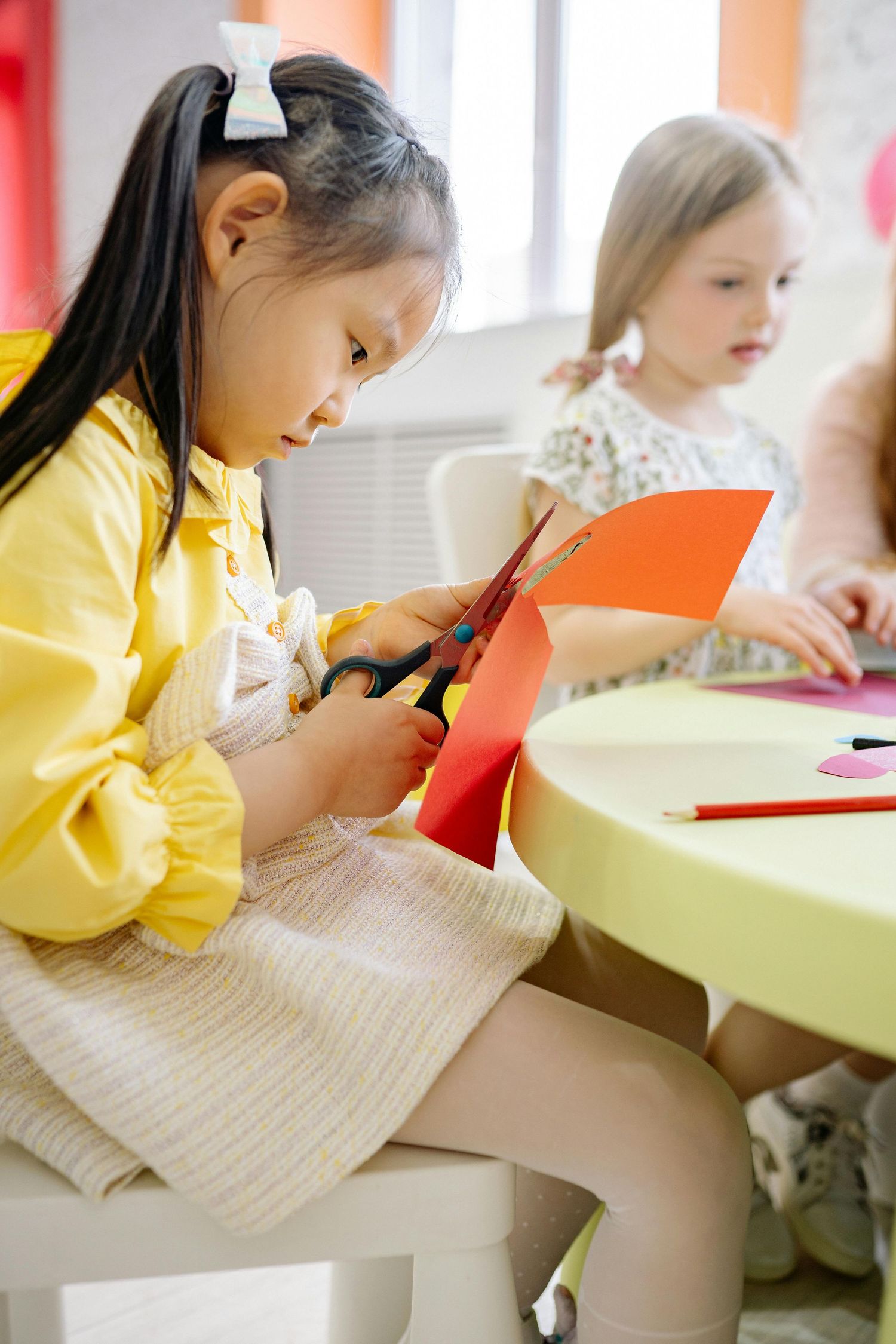 Queen Creek  Arizona Daycare Photography Students focused on writing and drawing activities at yellow desks.