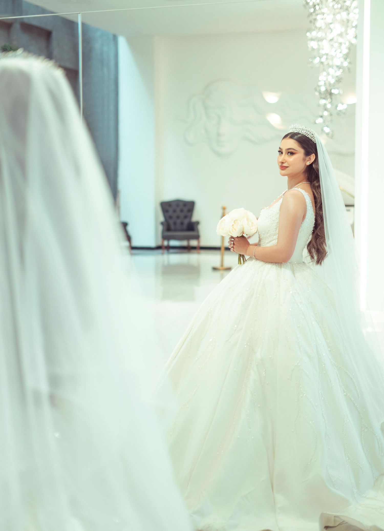A bride in a voluminous white ball gown poses gracefully in a light-filled modern interior space.  Award Winning Photographer Scottsdale.