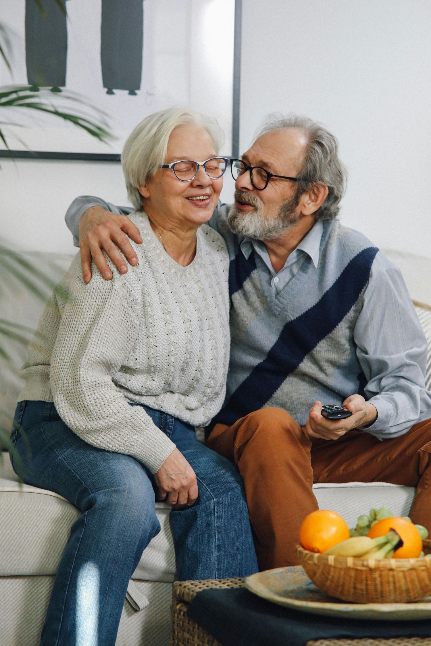 Elderly couple sitting on couch sharing affectionate moments while having healthy snacks in their arizona home