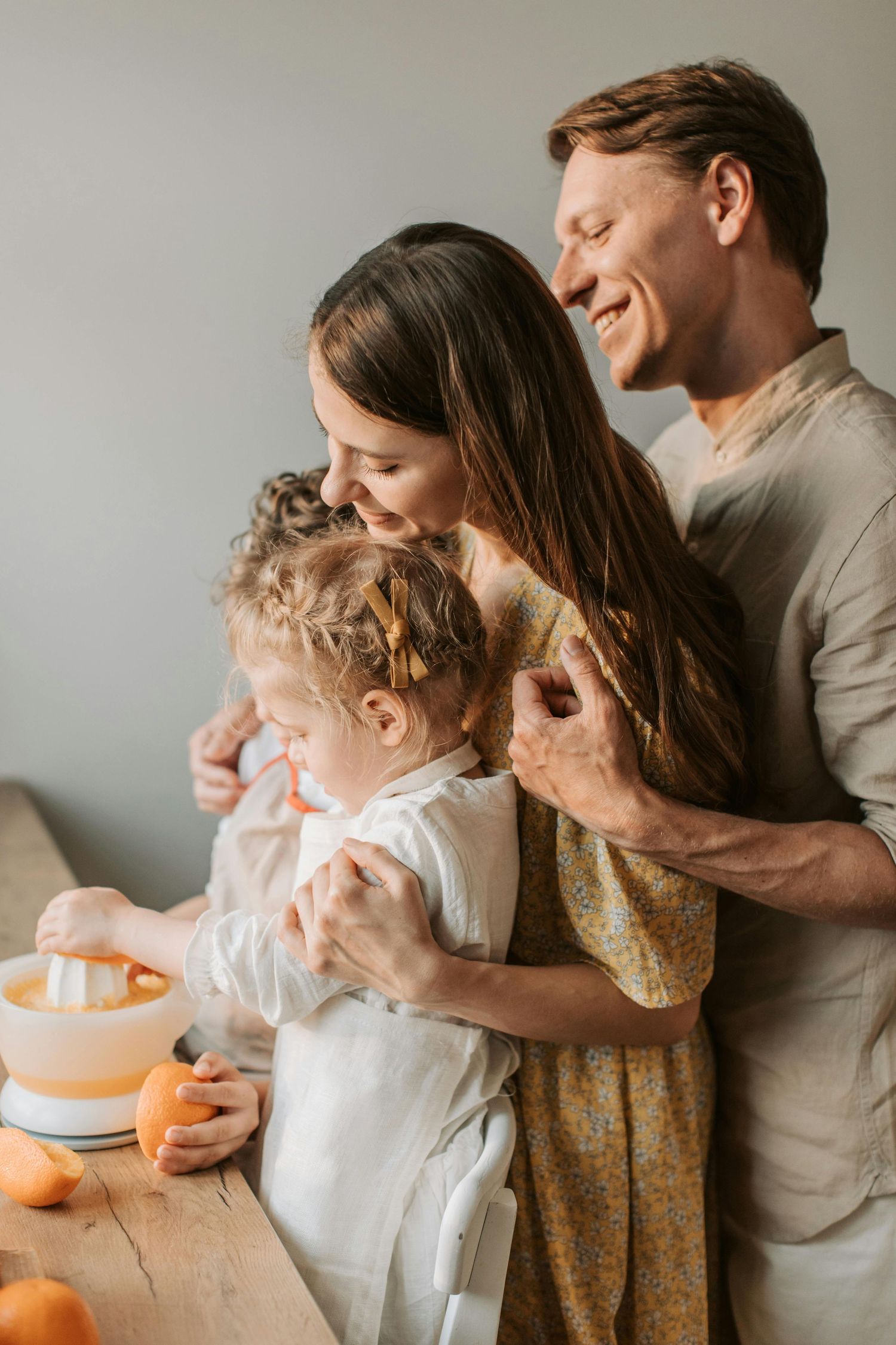 A family shares joyful moments while eating oranges together in a warm, naturally lit setting. Desert Ridge Arizona.