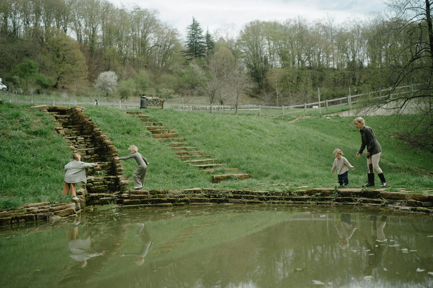 San Tan Valley Arizona Family Photography kids exploring wooden steps leading down to a pond in a lush green landscape.
