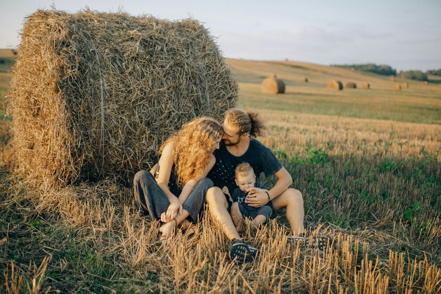 Paradise Valley Arizona Family Photography A family sits together near hay bales in a rustic farm field at sunset.