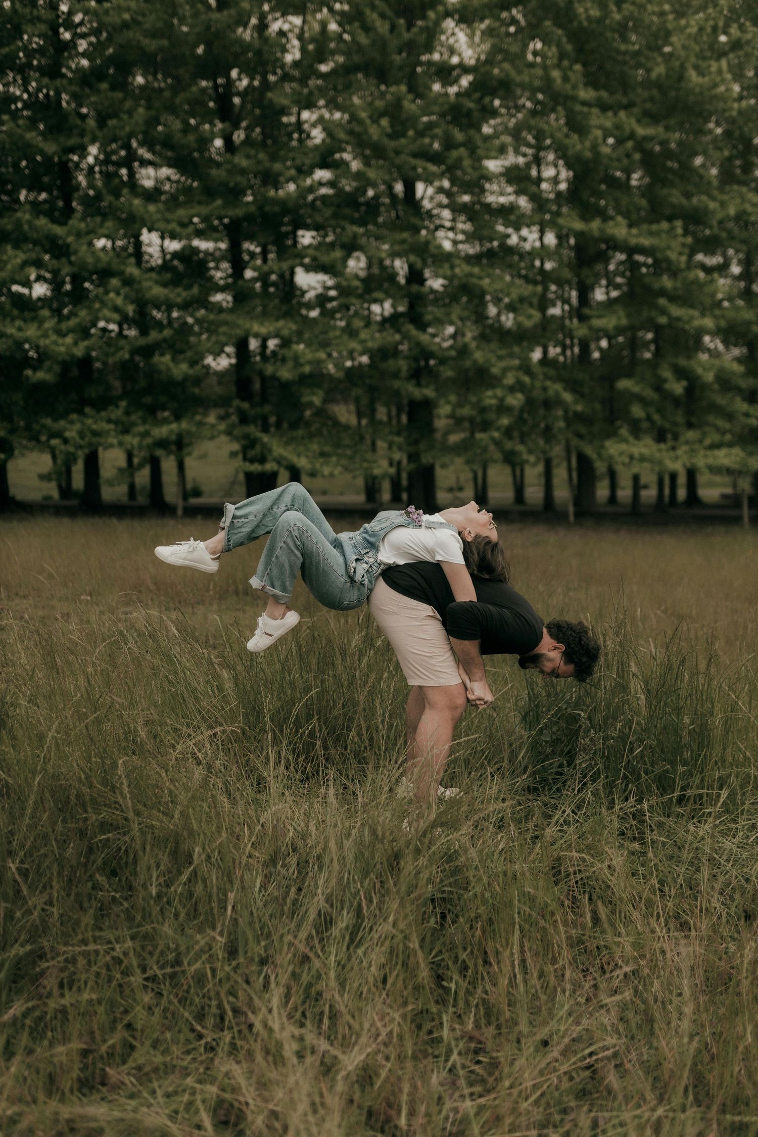 A person floating horizontally in a grassy meadow wearing a dress and boots against a wooded background. Best Photographer Phoenix.