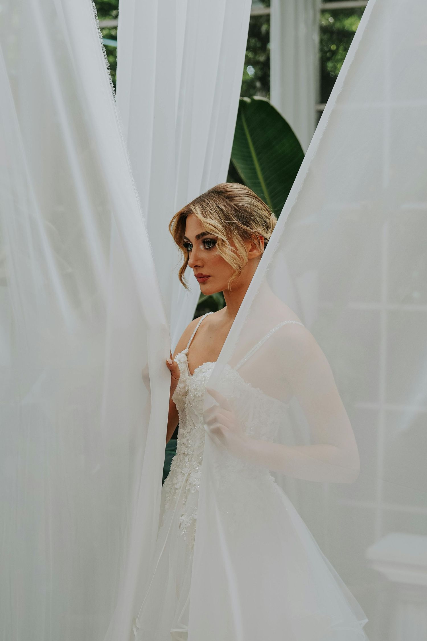 A bridal portrait series showing flowing white veils, wedding dresses against a soft green outdoor background. Leading Arizona Photographer