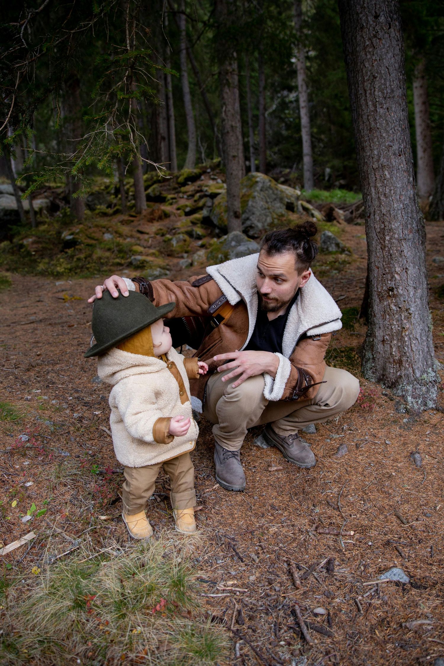 Sedona Arizona Portraits Someone pets a small brown dog while sitting on pine needles in a forest setting.