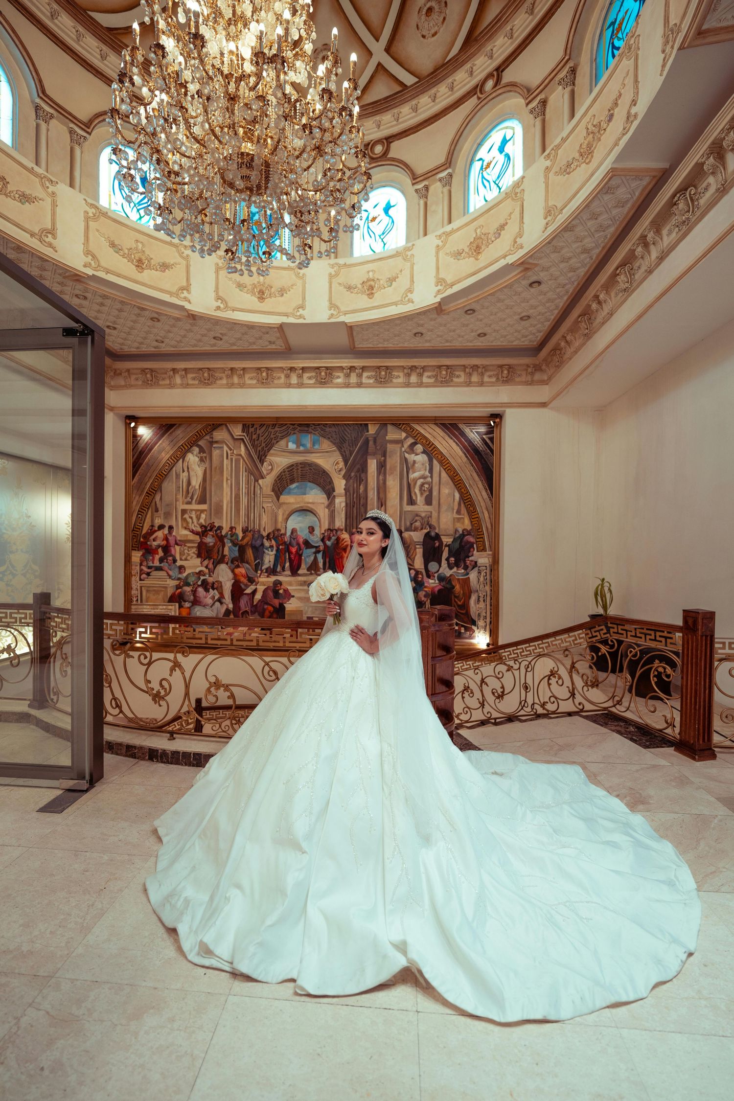 Ballroom with crystal chandeliers and ornate details showcases a flowing white wedding gown on display.  Award Winning Photographer