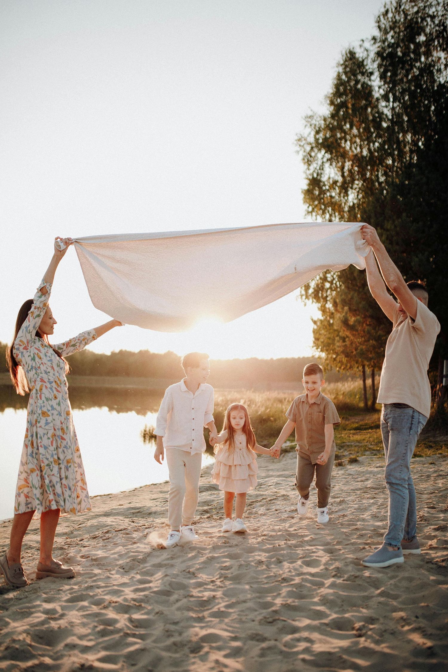 Prescott Arizona, mountaintop Family photography, Family holding up a white sheet together on a sandy beach at sunset.