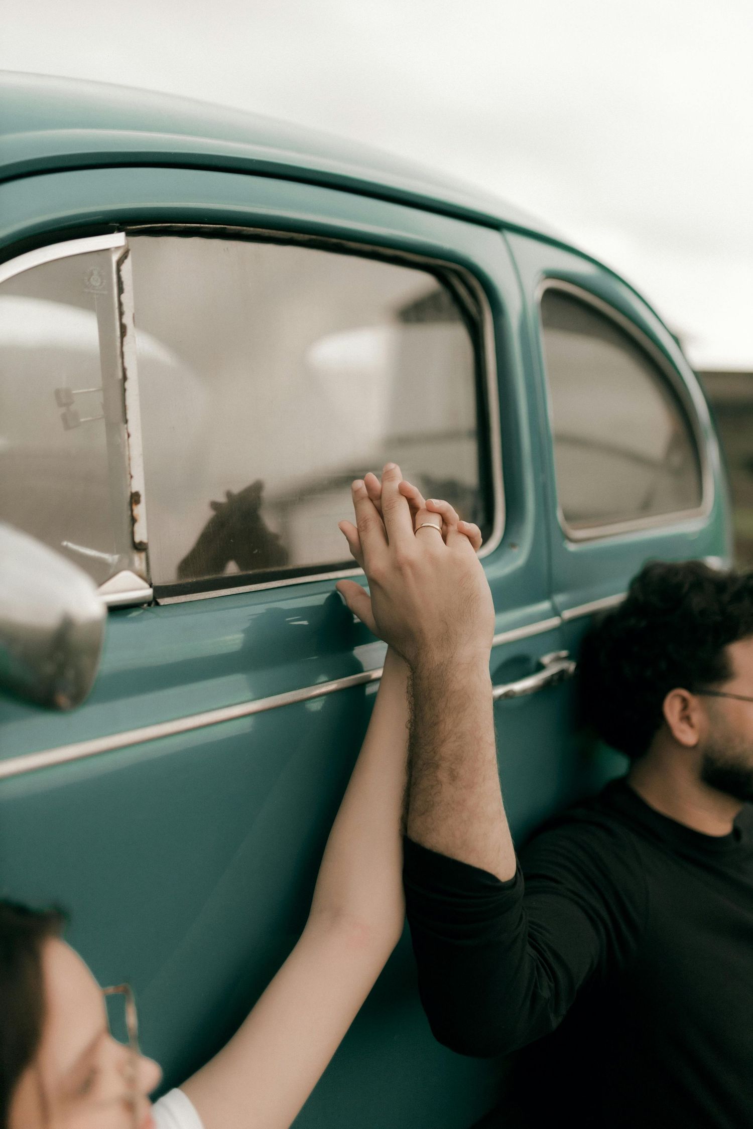 People reaching up to touch a vintage teal-colored car window on an overcast day. Best Photographer Phoenix.