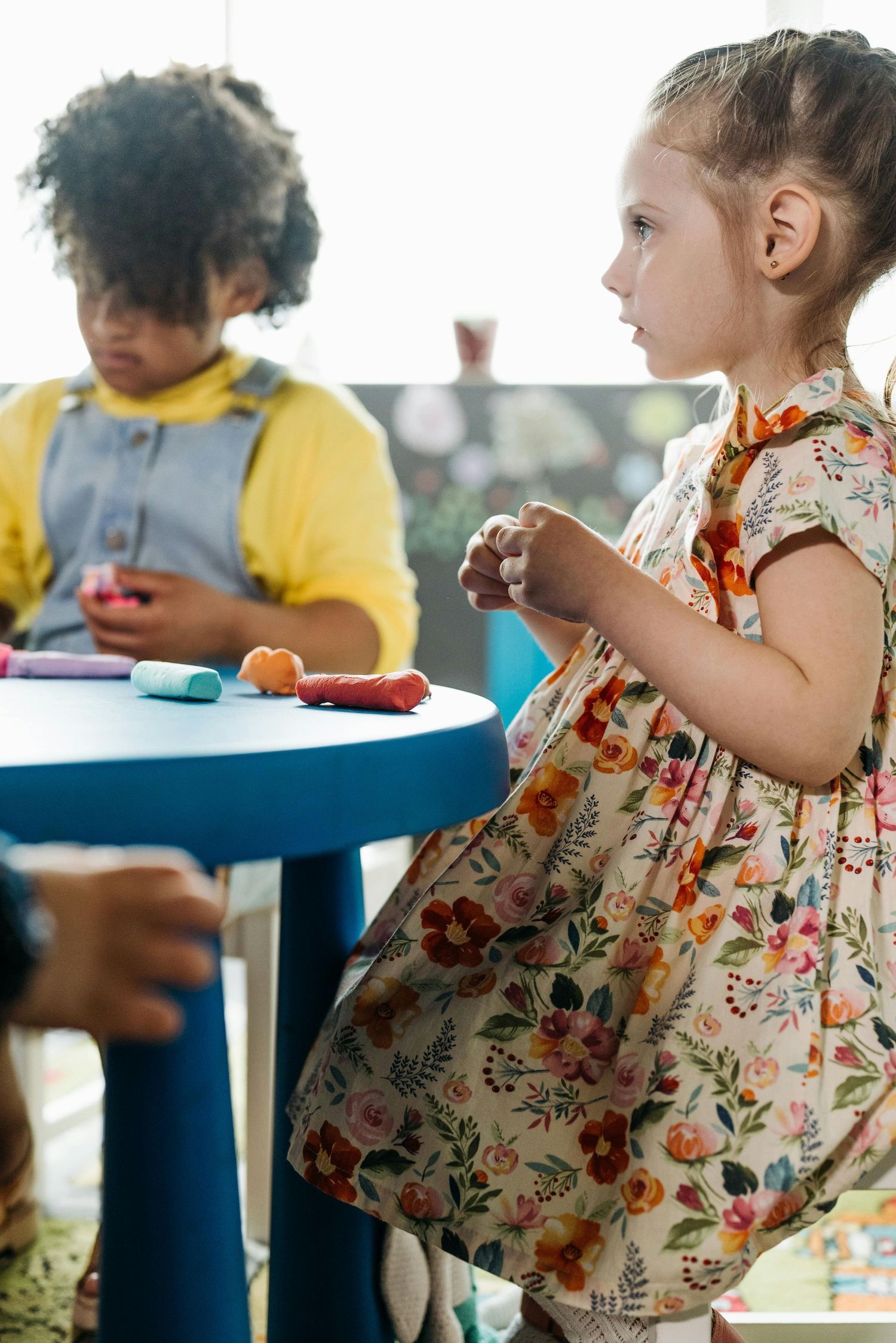 Arizona Daycare Photography Children sitting at blue tables wearing colorful clothing during activity time.