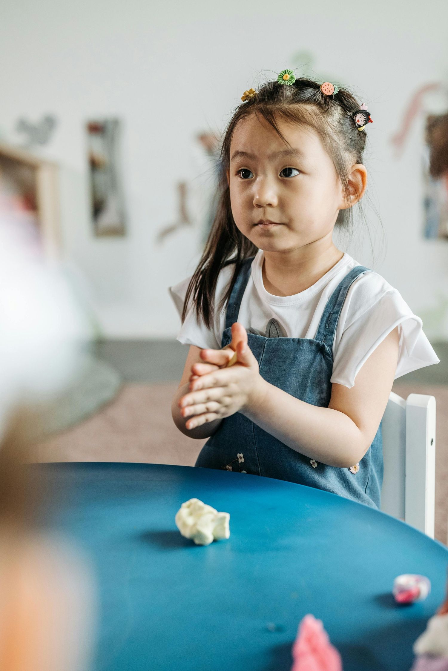 Scottsdale Arizona Photography Child in denim overalls sitting at a blue table during playtime.