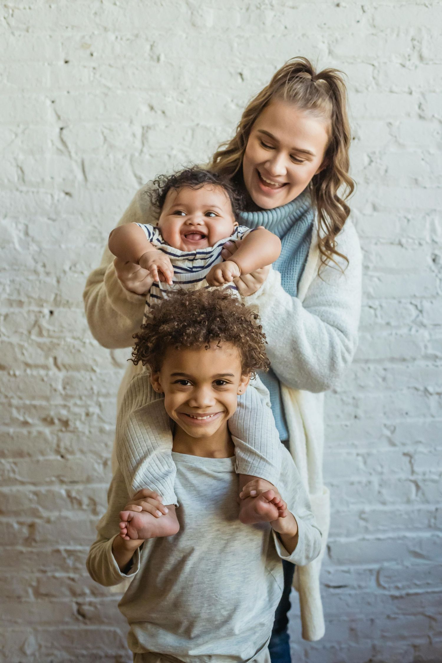 Family Studio Portraits Sedona. A joyful moment captured in a series of playful interactions against a white brick wall background.