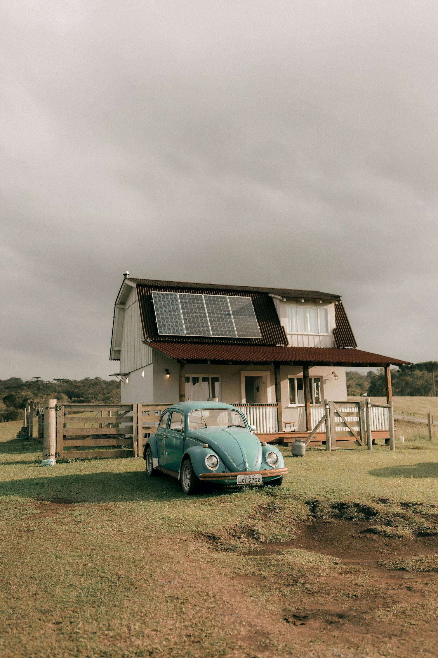 A rustic house with solar panels on the roof and a vintage blue Volkswagen Beetle parked in front on a cloudy day. Best Photographer Phoenix