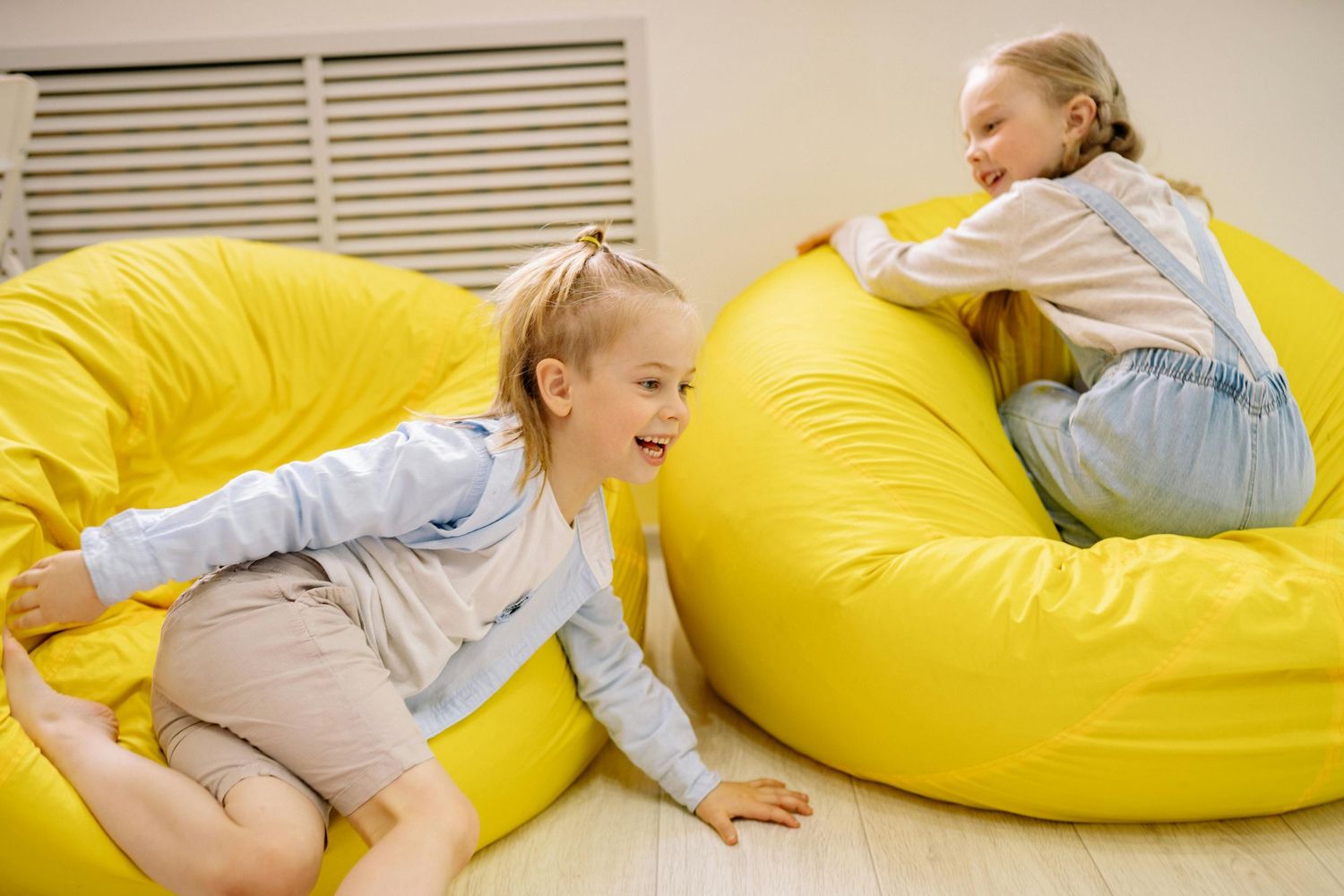 Queen Creek  Arizona Daycare Photography Children playing and having fun on yellow bean bag chairs in a classroom.