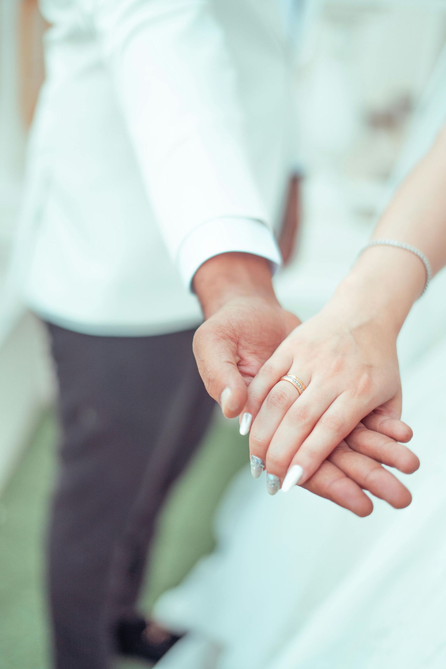 Close-up of two people holding hands tenderly while wearing formal white and black attire. Award Winning Photographer Tempe