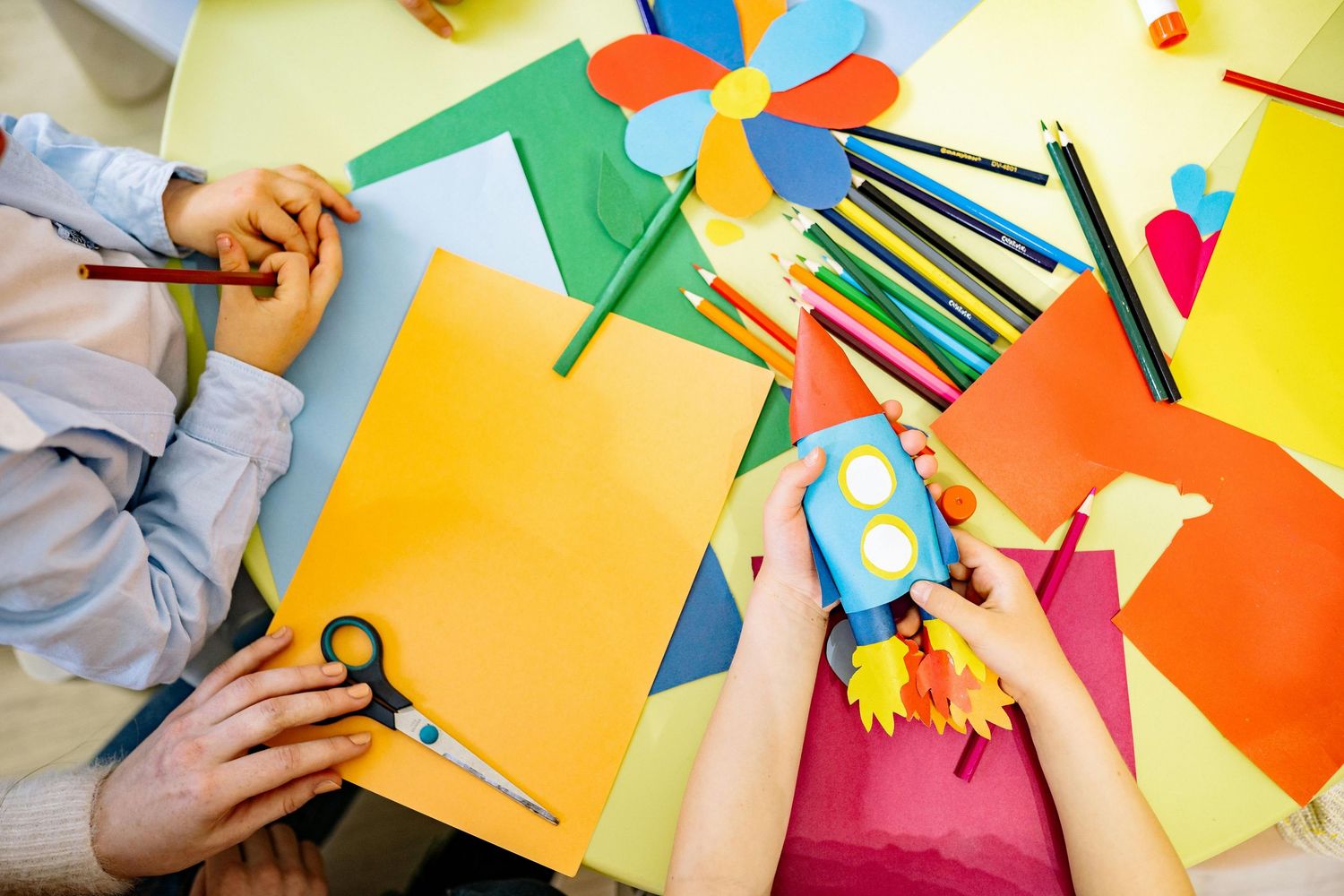Colorful art supplies and craft materials spread out on a yellow table surface. Peoria Vistancia