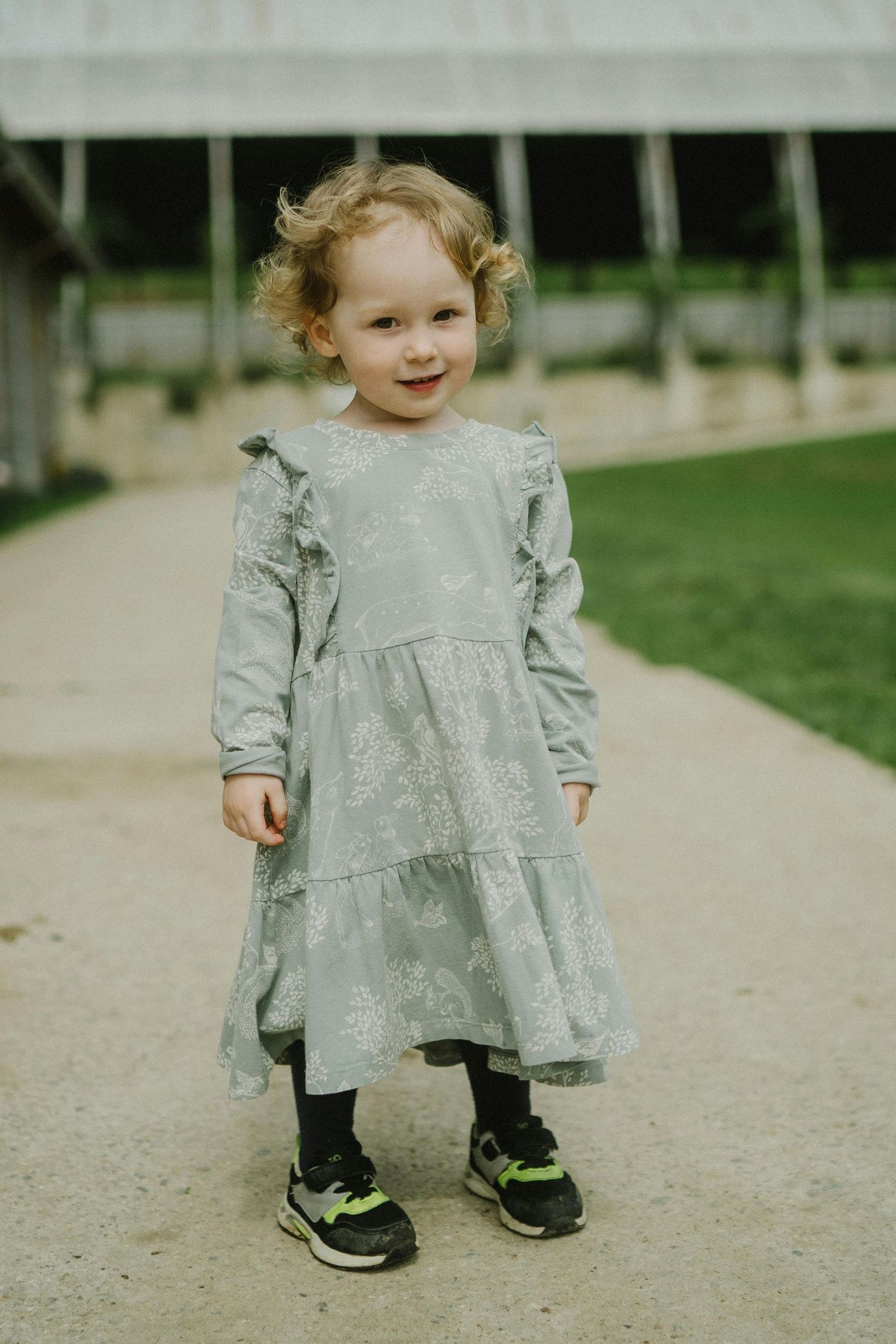 San Tan Valley Arizona Family Photography A toddler in a ruffled gray dress and sneakers stands on a path with a sweet smile.