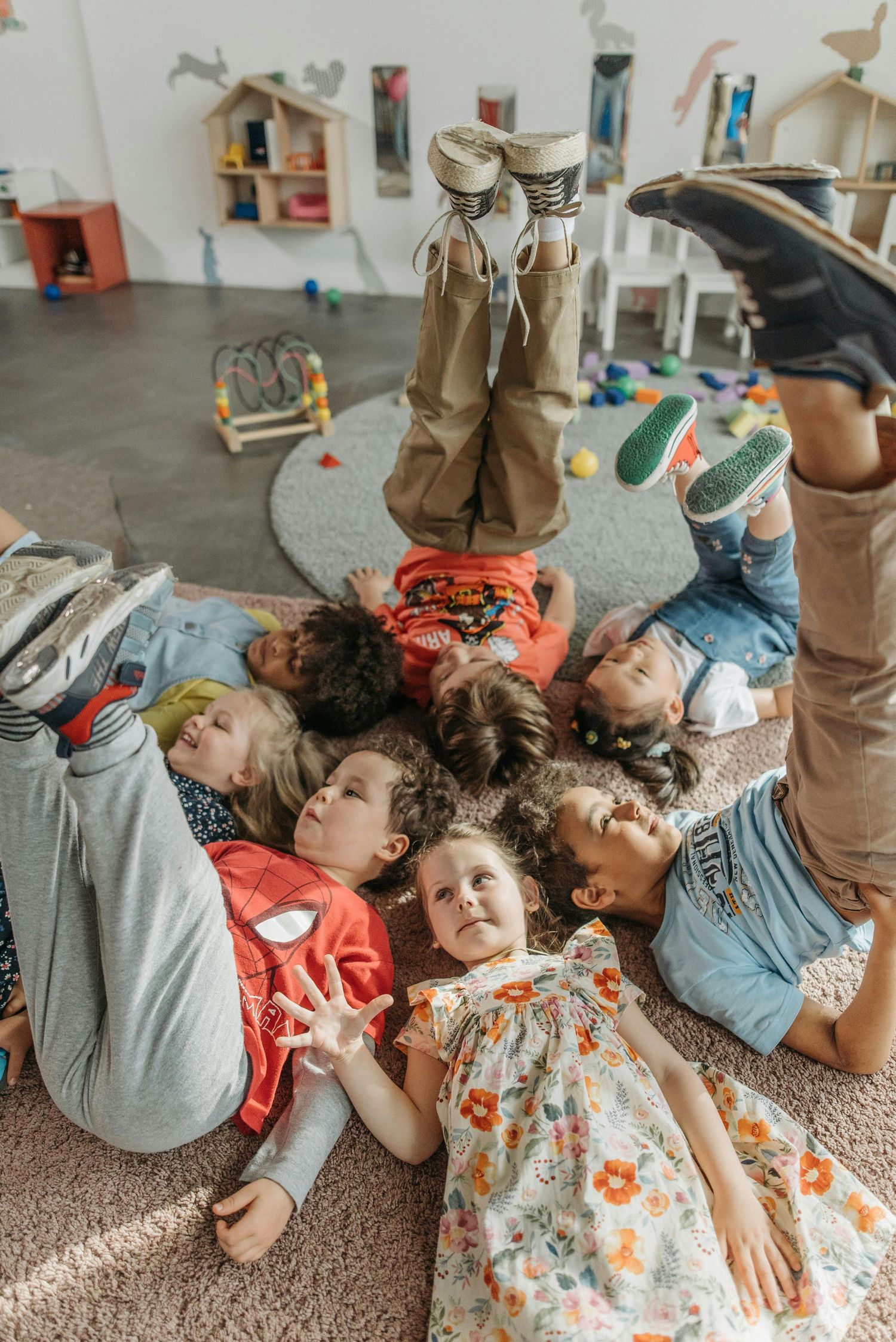 Group lying on carpet in playroom with feet up and heads together in circle formation while relaxing on floor. Old Town Scottsdale Arizona