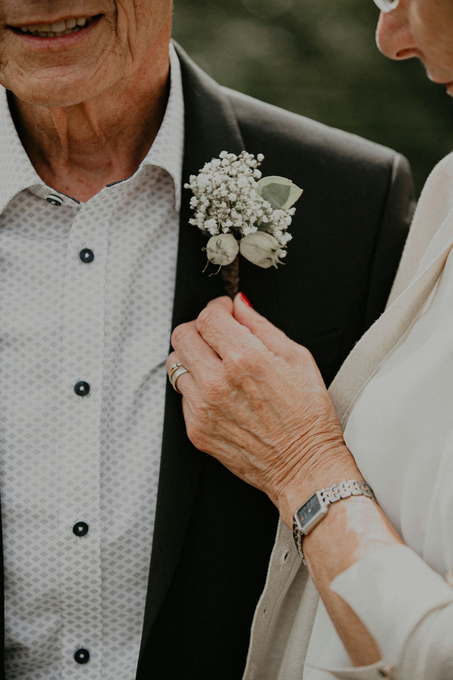 Close-up details of formal white dress shirts with buttons and boutonniere flowers at an elegant wedding celebration.