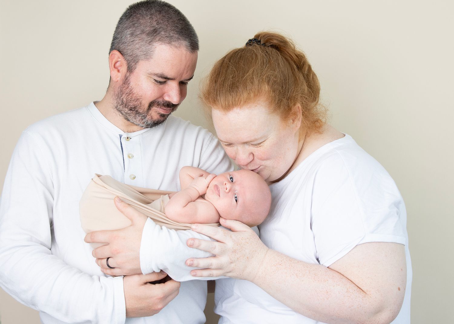 Parents cuddling their newborn baby during a family photography session in Tower Cork.