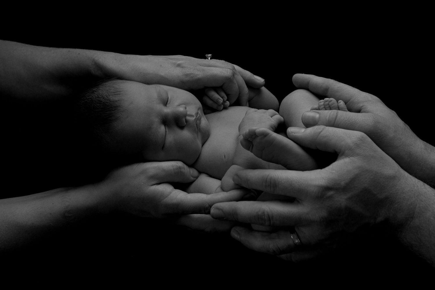 Newborn Photography image in black and white of baby in new parents hands