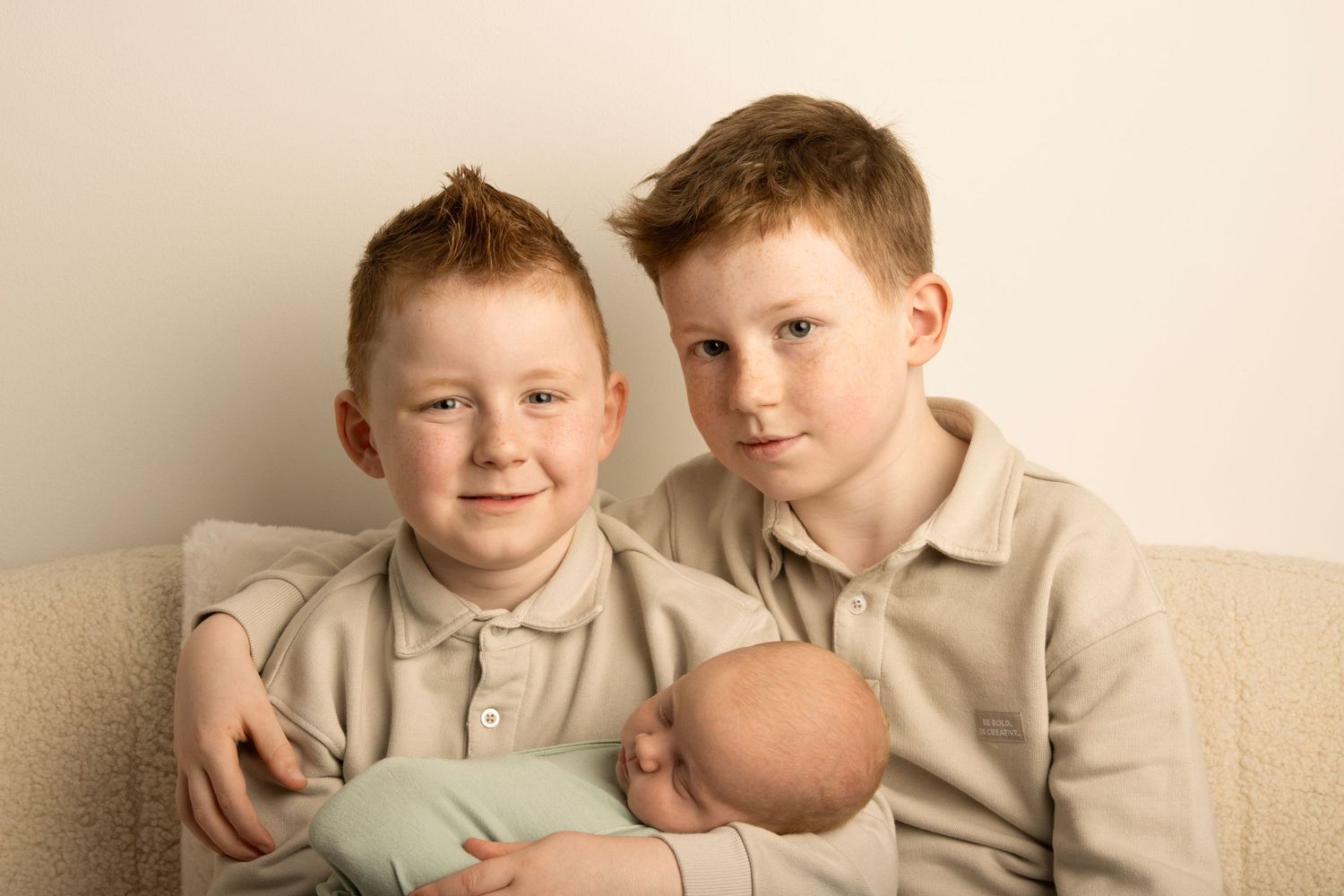 Newborn baby photographed in her siblings arms