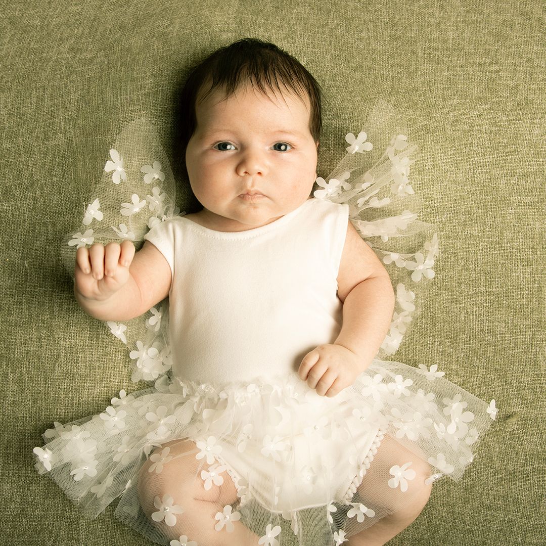 Baby girl wearing a white dress during a milestone photography session by a photographer in Tower Cork