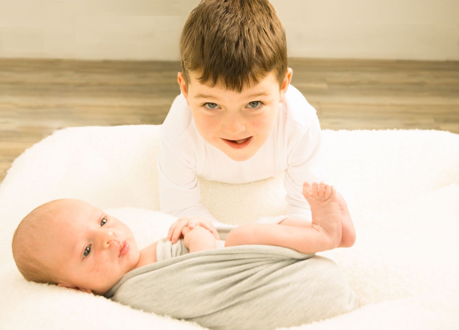 Older sibling interacting with newborn baby during a family photography session.