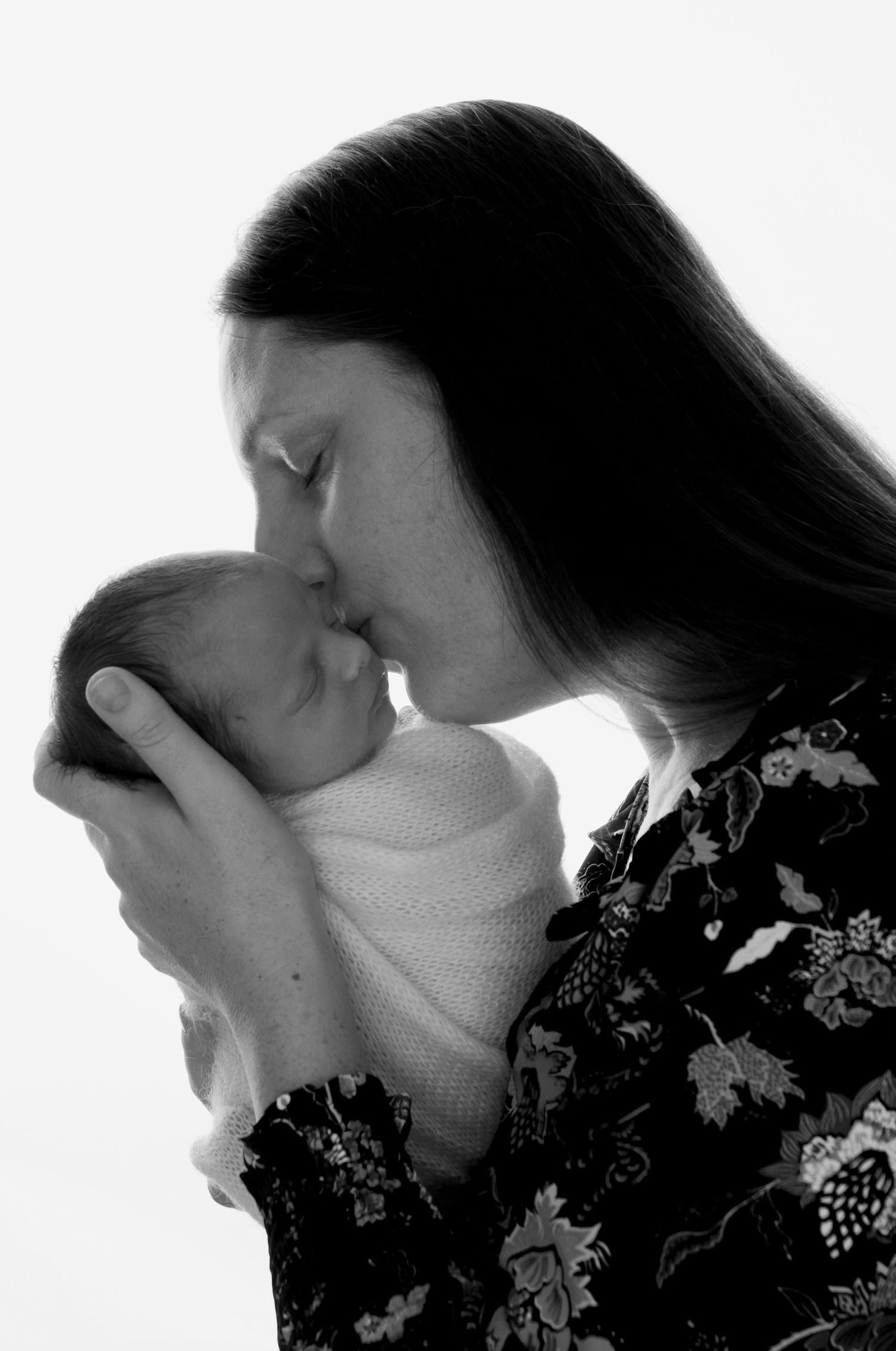 Black and white image of Mother kissing newborn baby during photography session in Tower near Blarney Cork