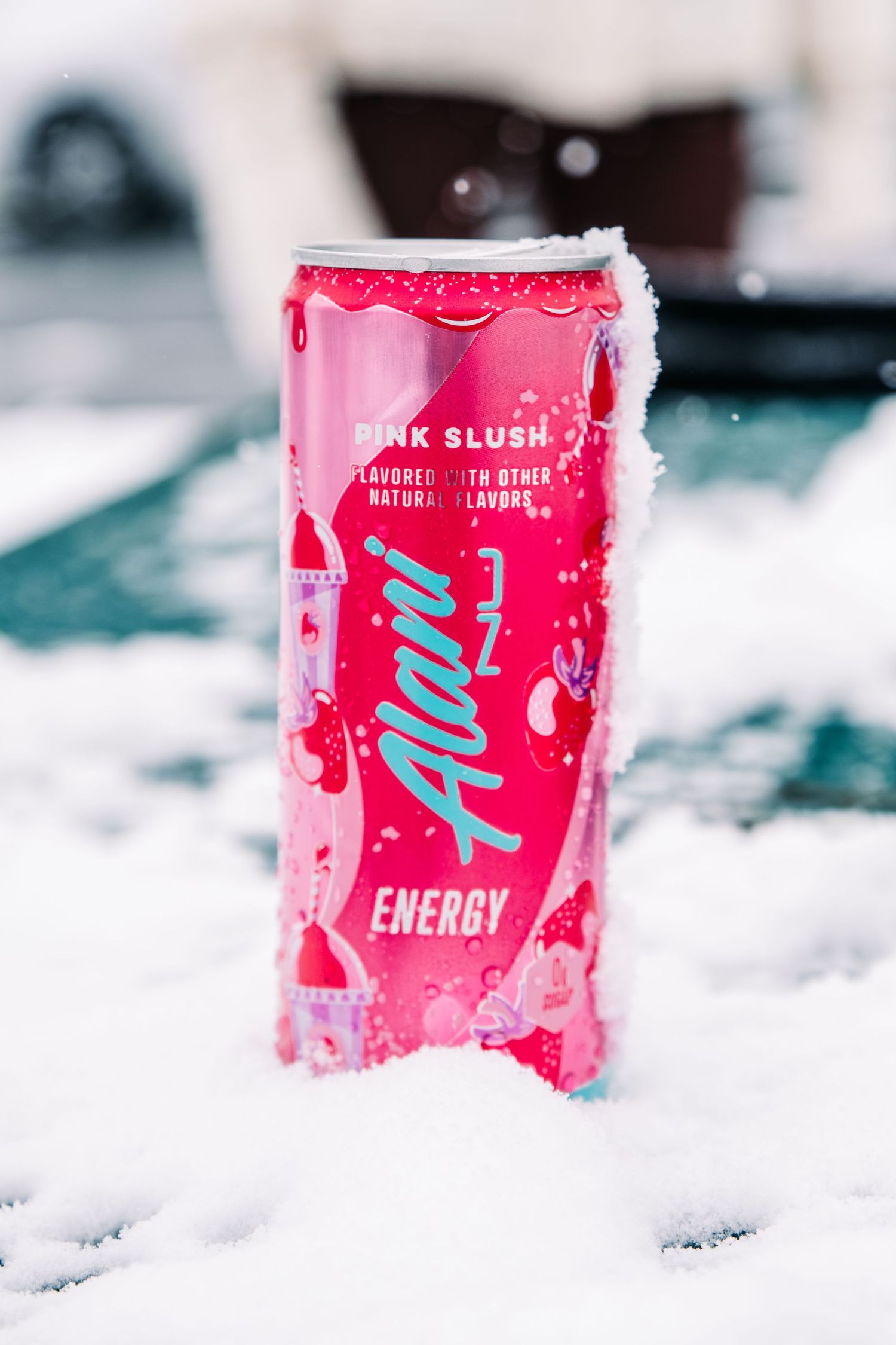 Pink Alani Nu energy drink cans chilling in fresh snow with winter bokeh background effect.