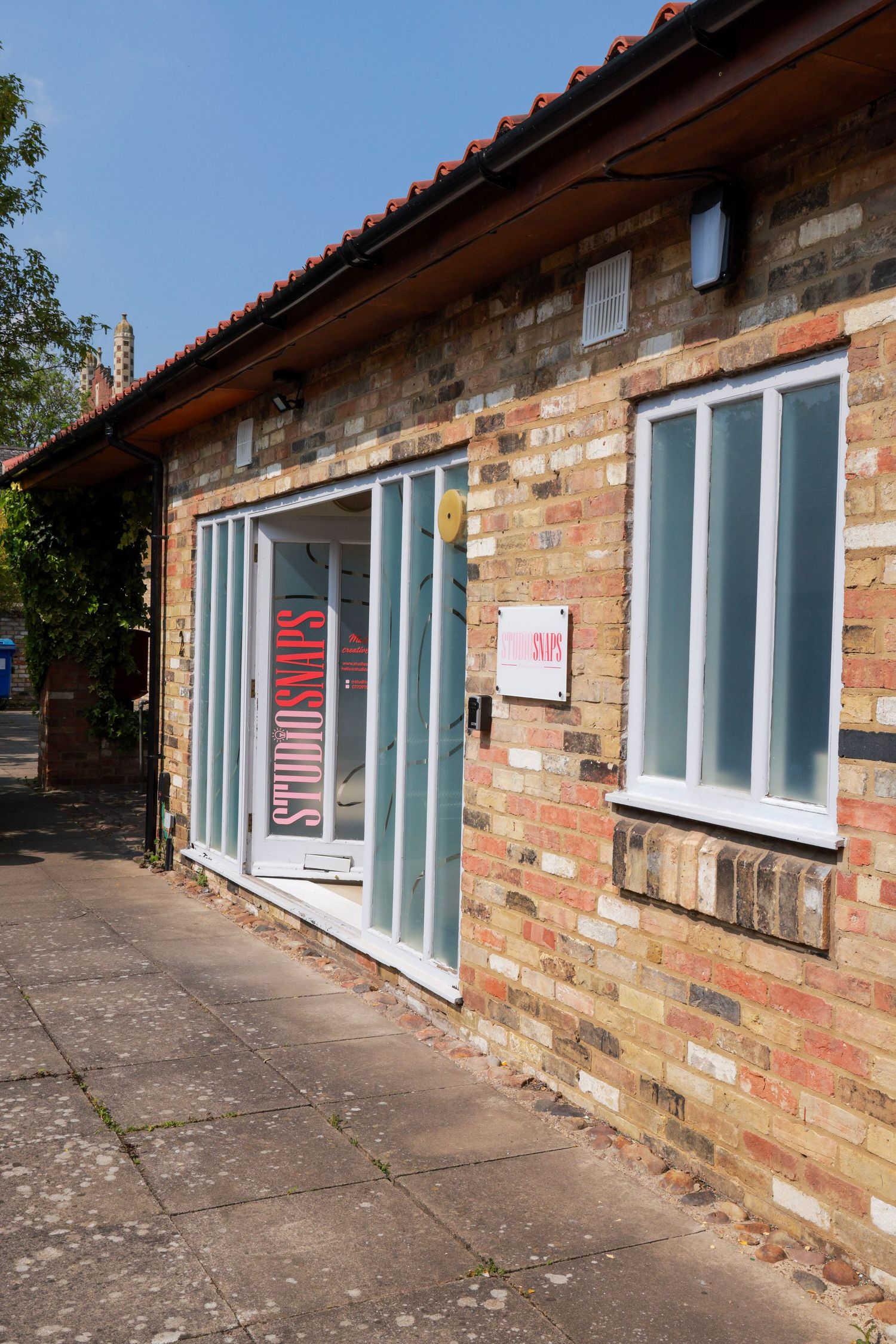 Exterior view of brick building with multiple white-framed windows in a row.