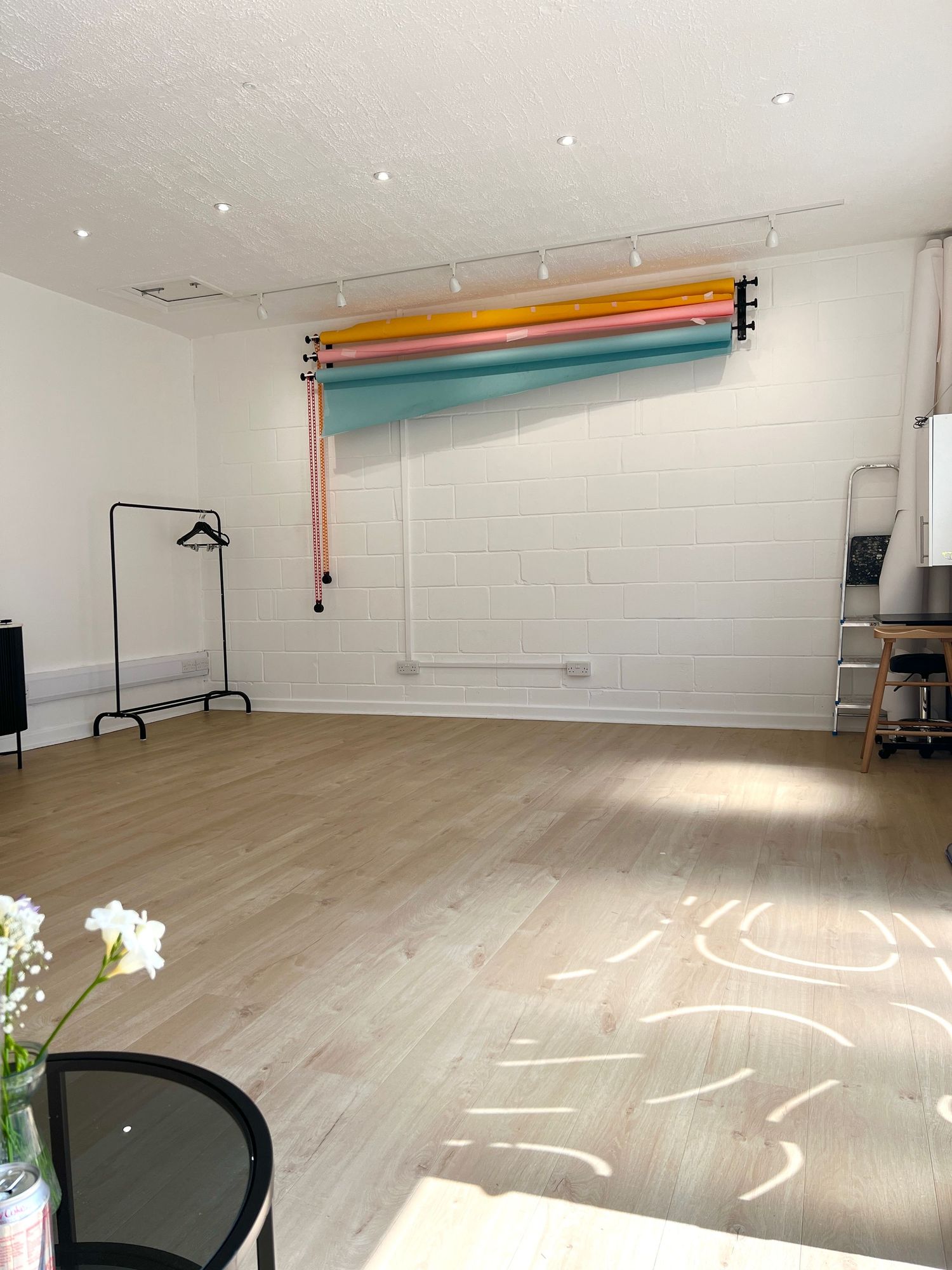 Large empty studio room with white walls and colorful lighting equipment mounted on ceiling.