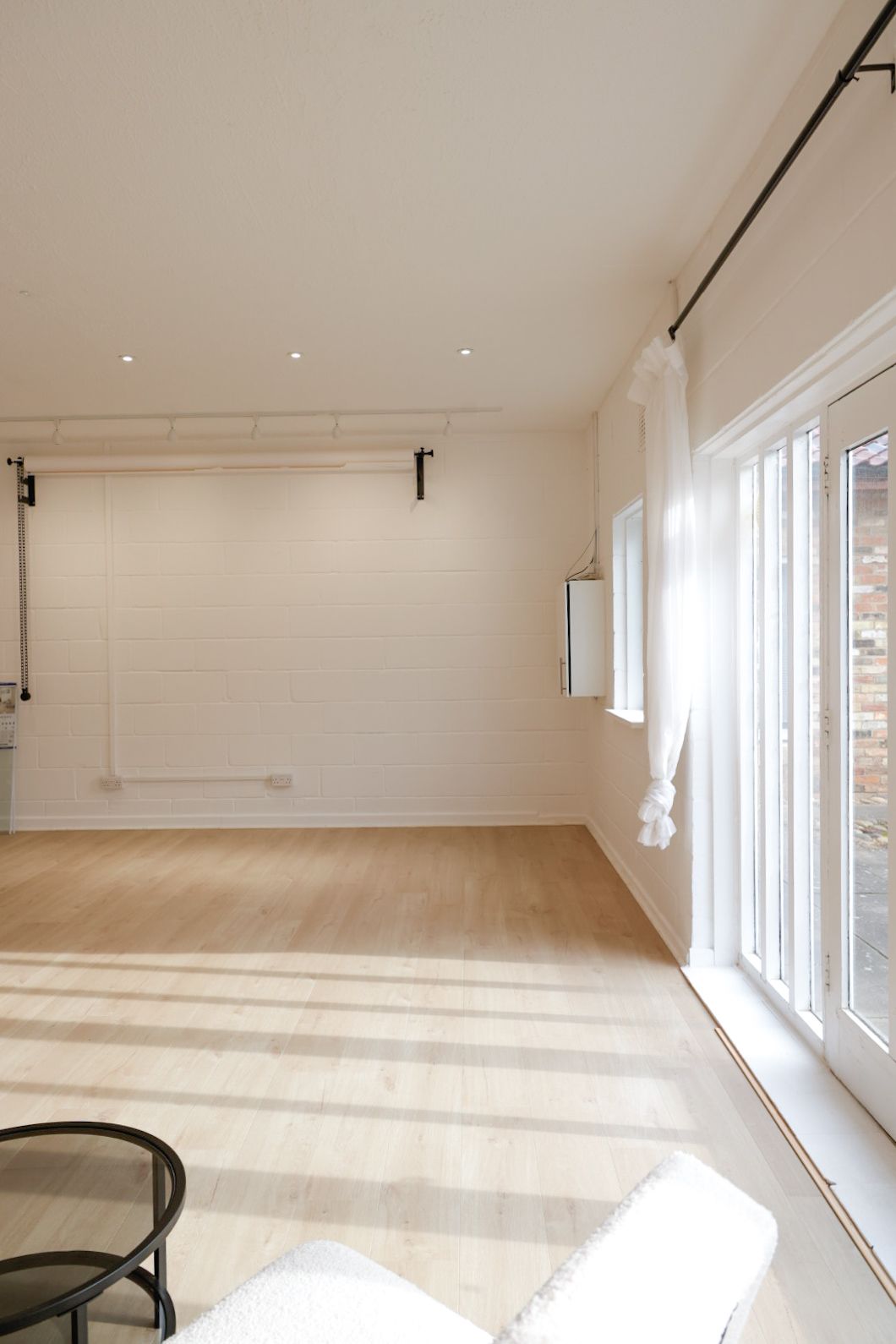 Empty white studio space with hardwood floors and large windows.