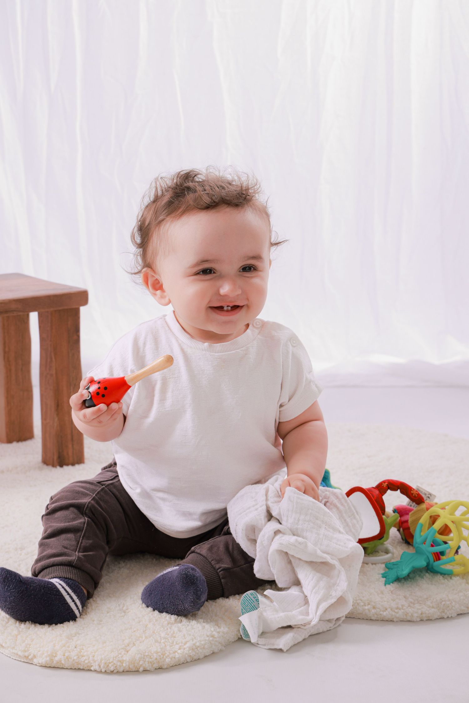 Baby crawling on white carpet with colorful toys and blanket showing exploration and movement.