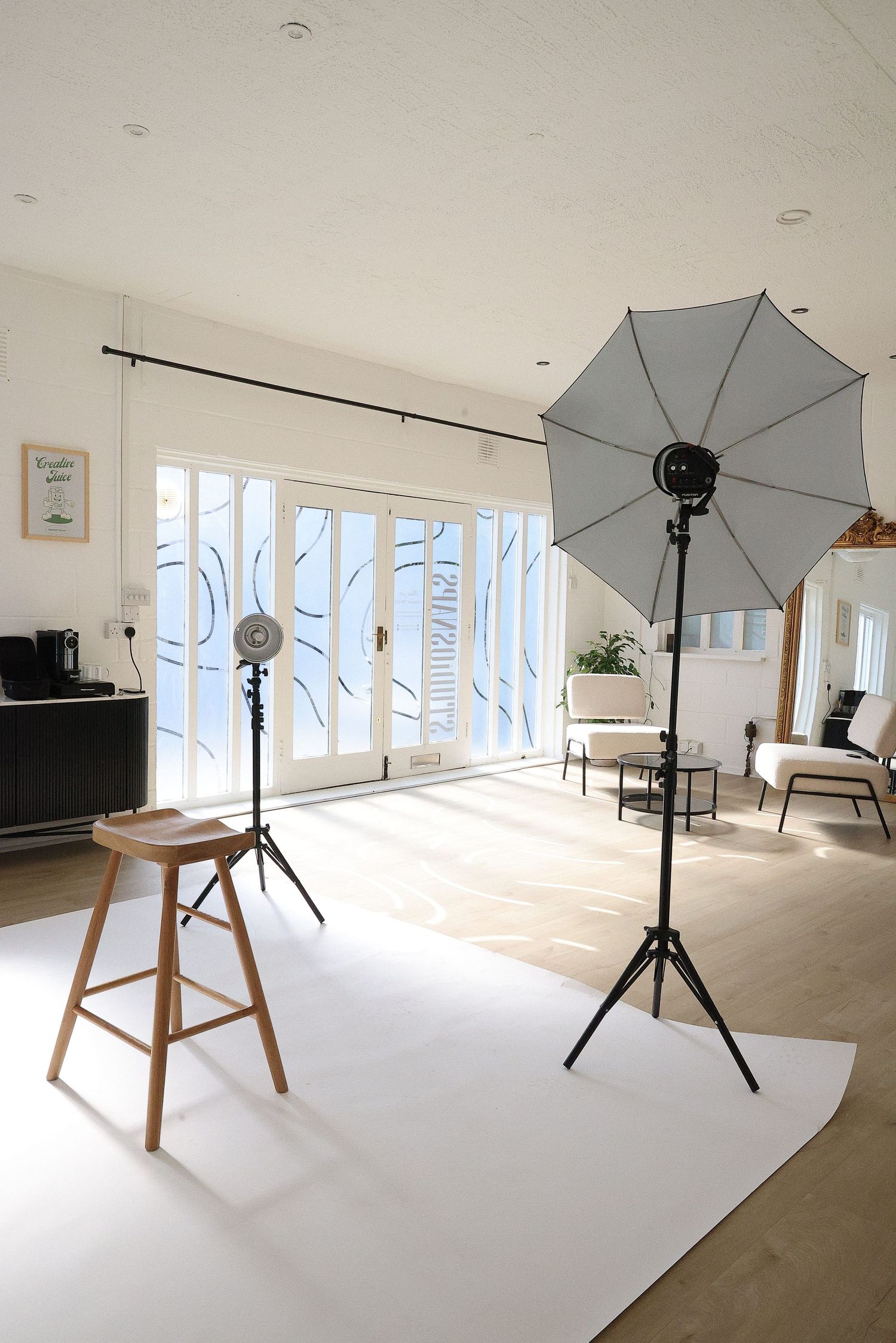 Photography studio setup with white backdrop and lighting equipment.
