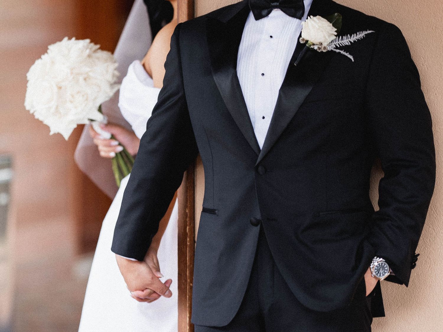 Classic groom details showing black tuxedo with white boutonniere and bow tie.