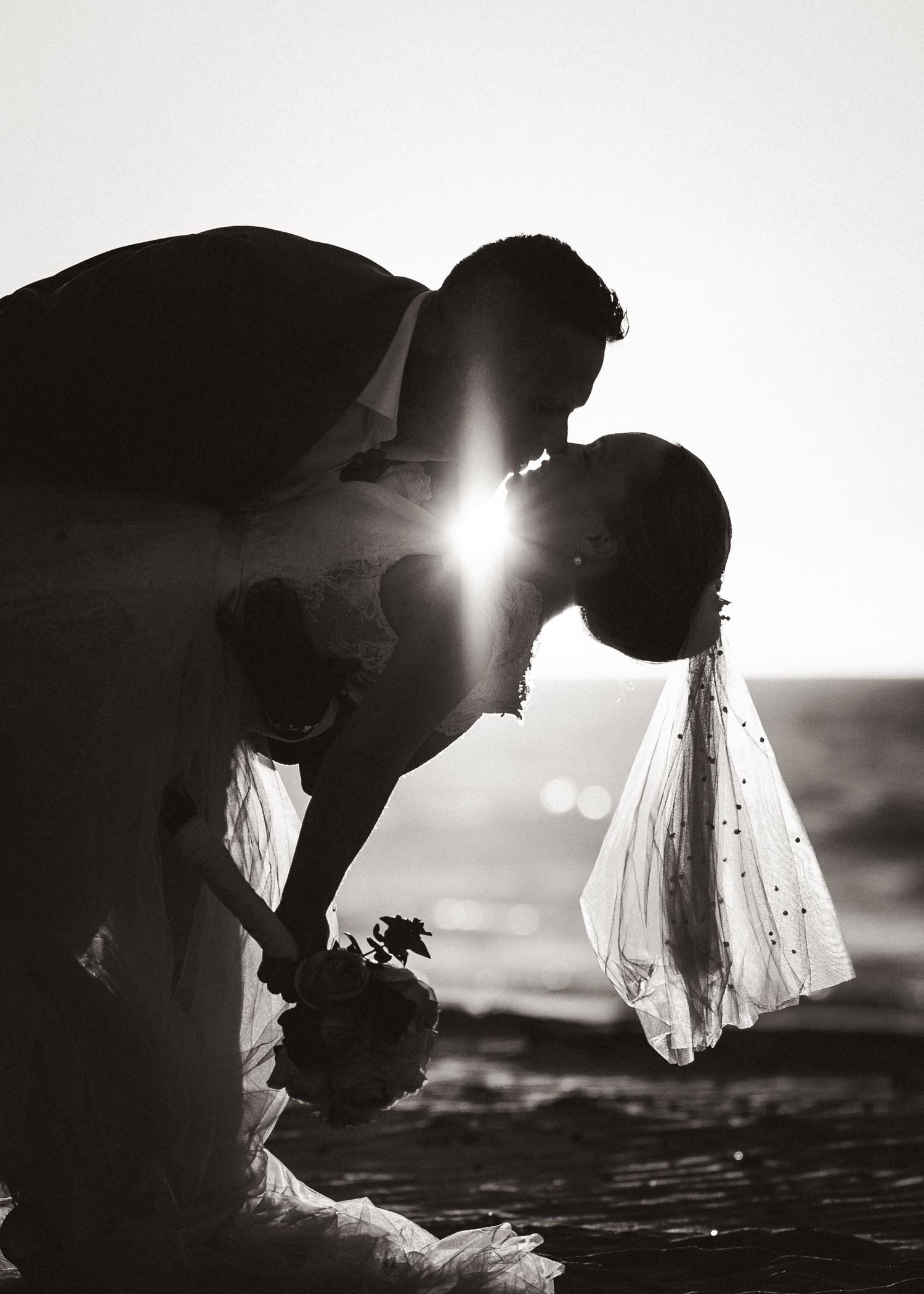 A romantic silhouette of a couple sharing an intimate moment at sunset with dramatic backlighting.