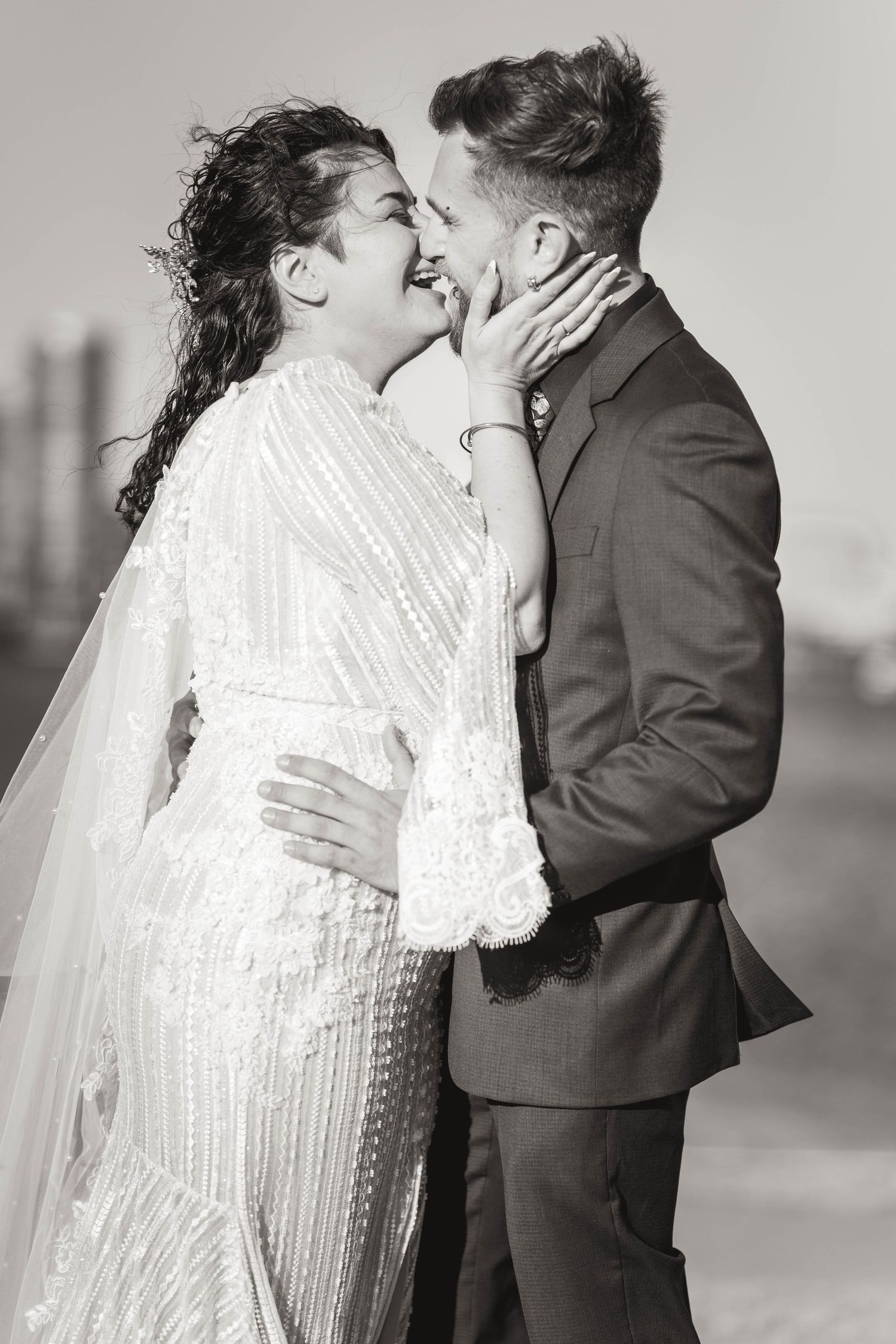 Romantic wedding couple in black and white sharing an intimate kiss with bride in beaded gown.