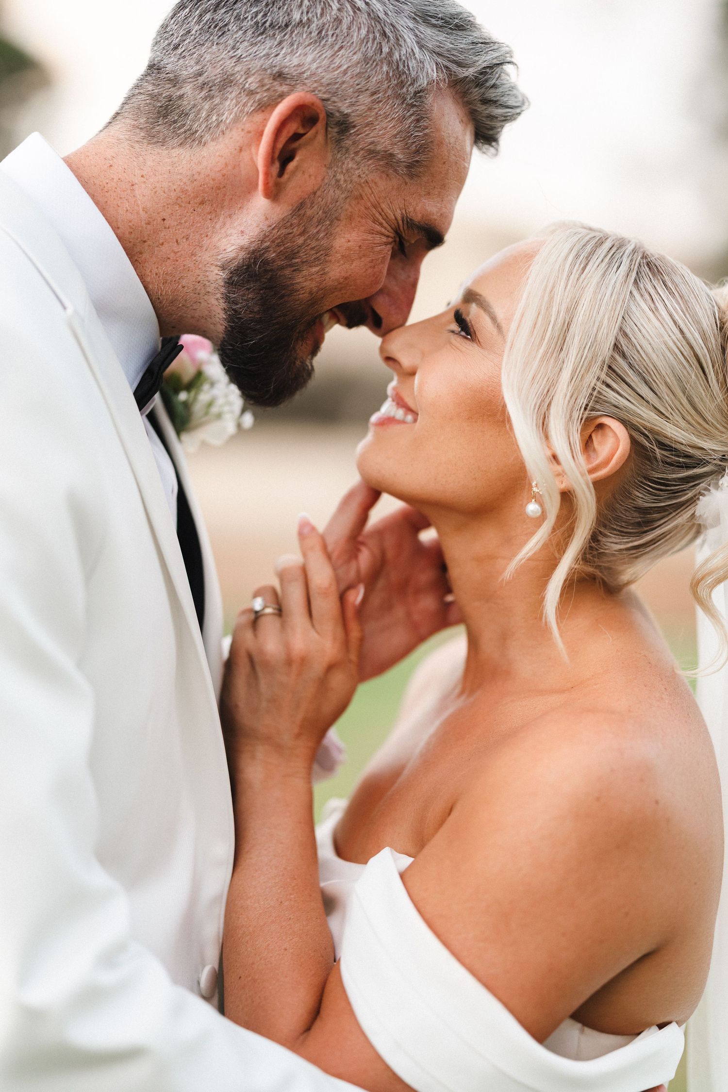 A romantic wedding moment captured in soft lighting as a couple shares an intimate close embrace.